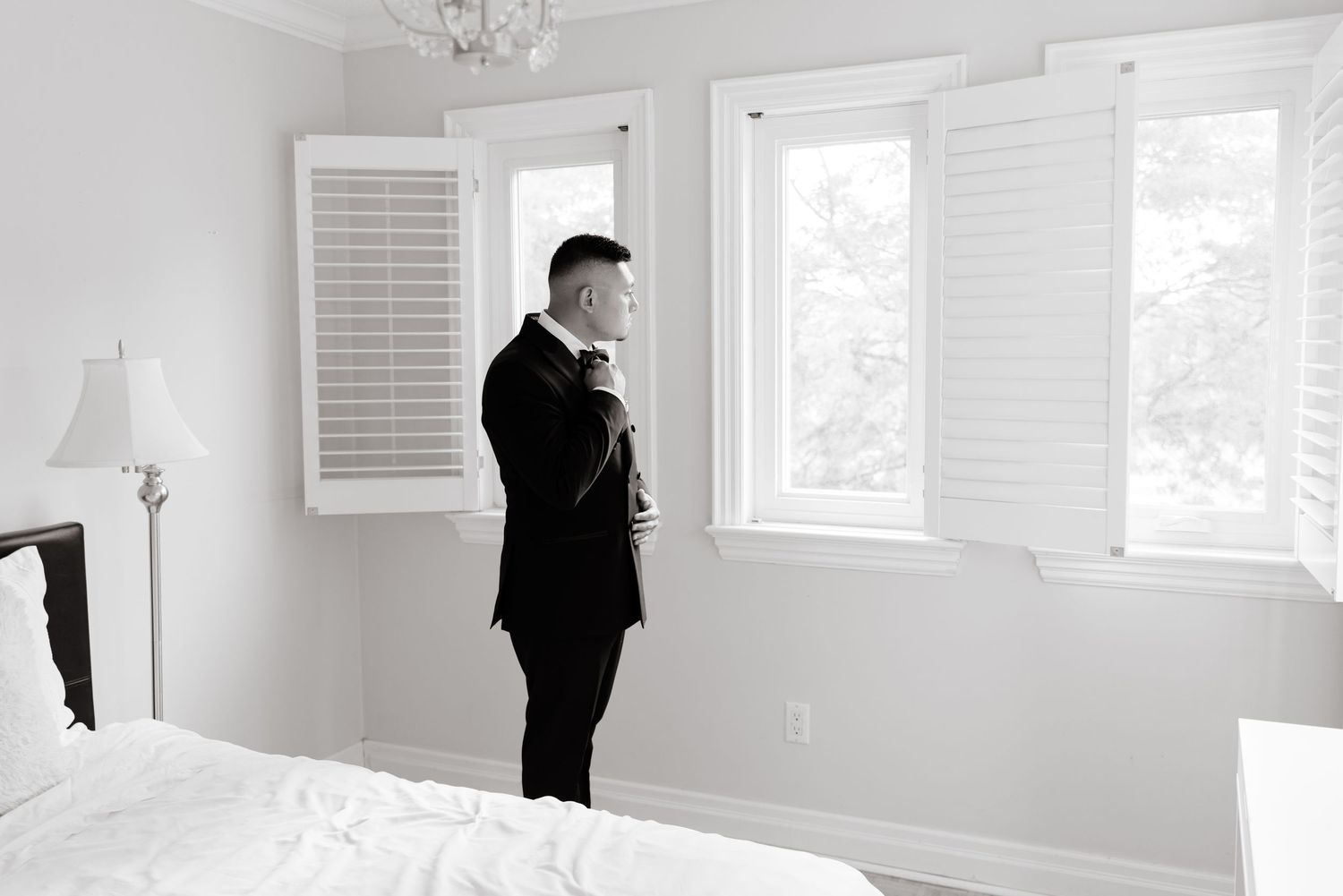 A bright white bedroom interior with shuttered windows showcasing modern minimalist design elements.