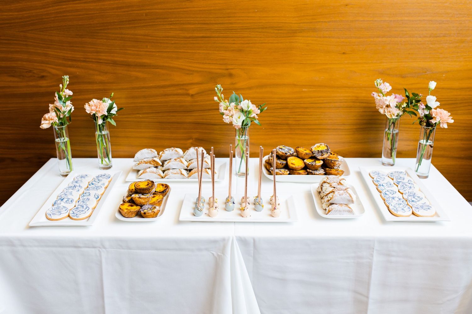 White dessert table with small floral arrangements and carefully arranged sweets.
