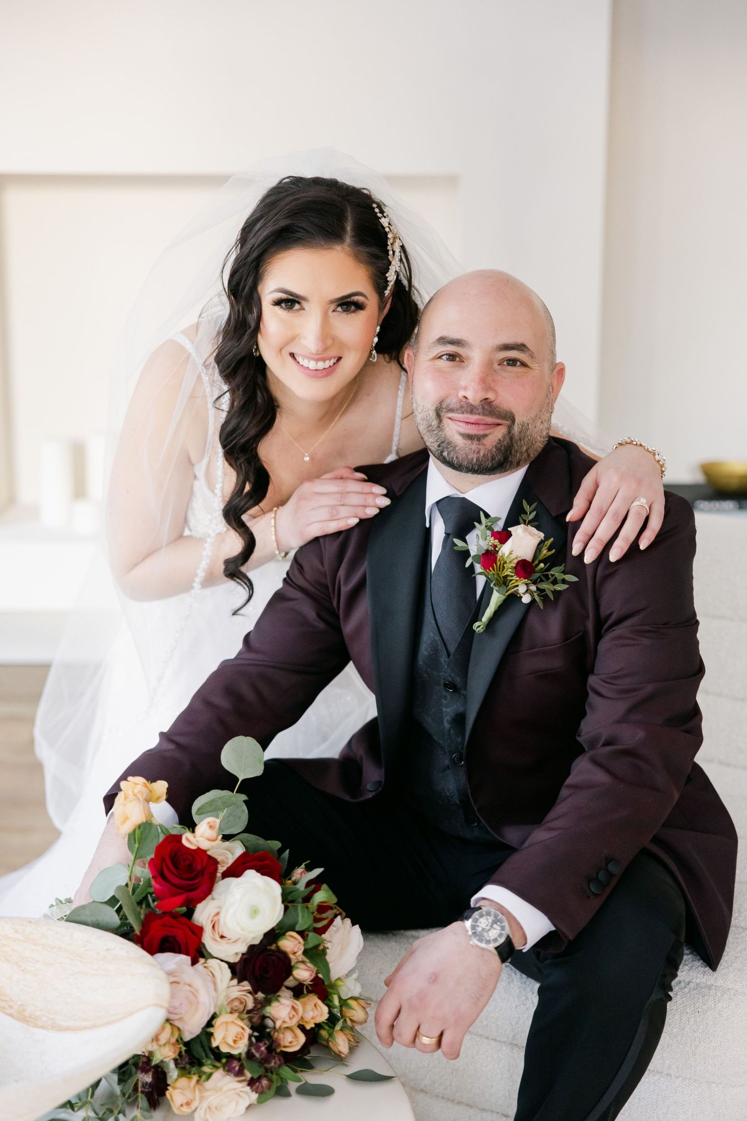 A wedding portrait in a bright modern space with red floral accents.