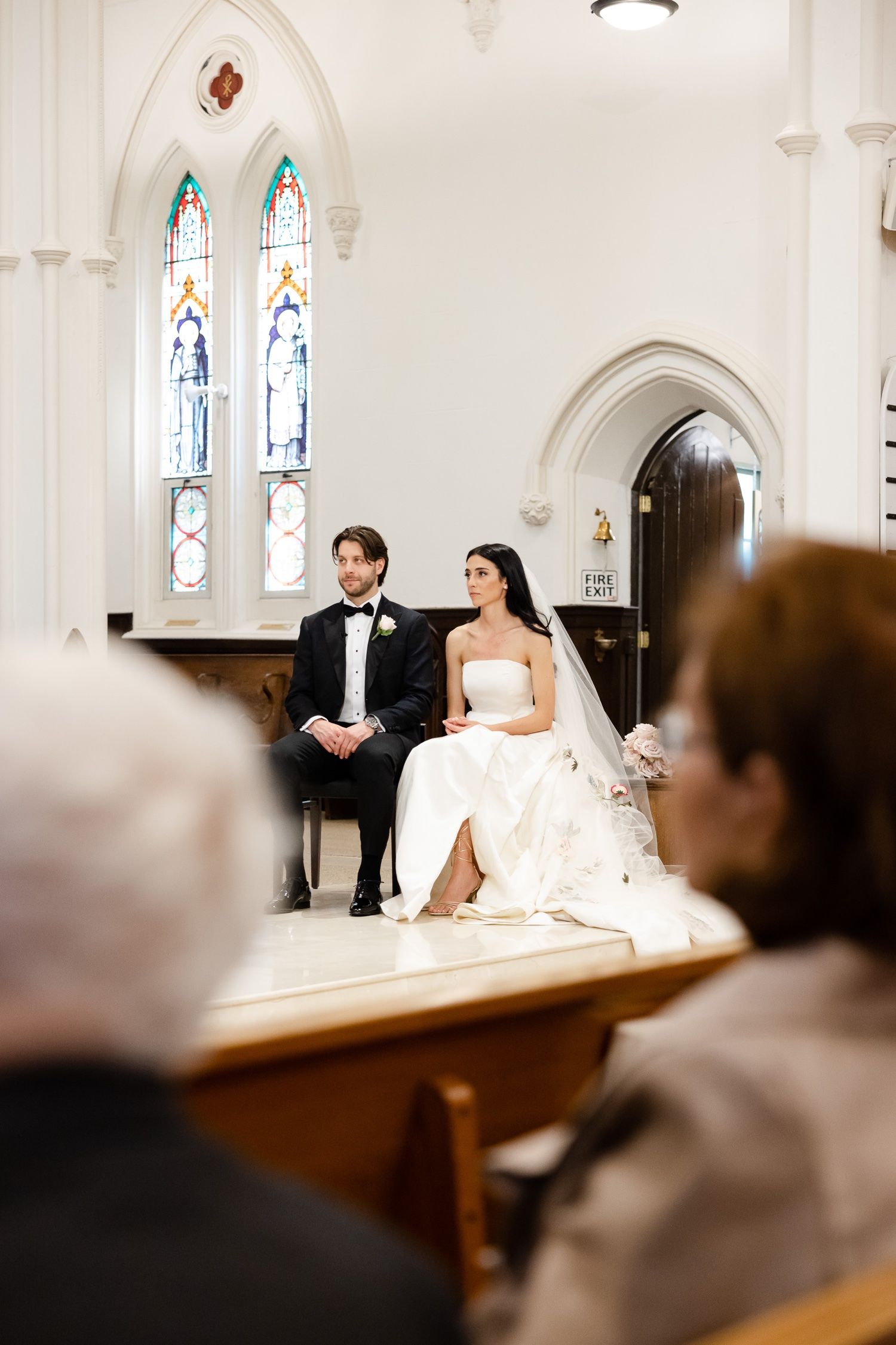 Wedding ceremony in a historic church with Gothic arched windows and white architectural details.