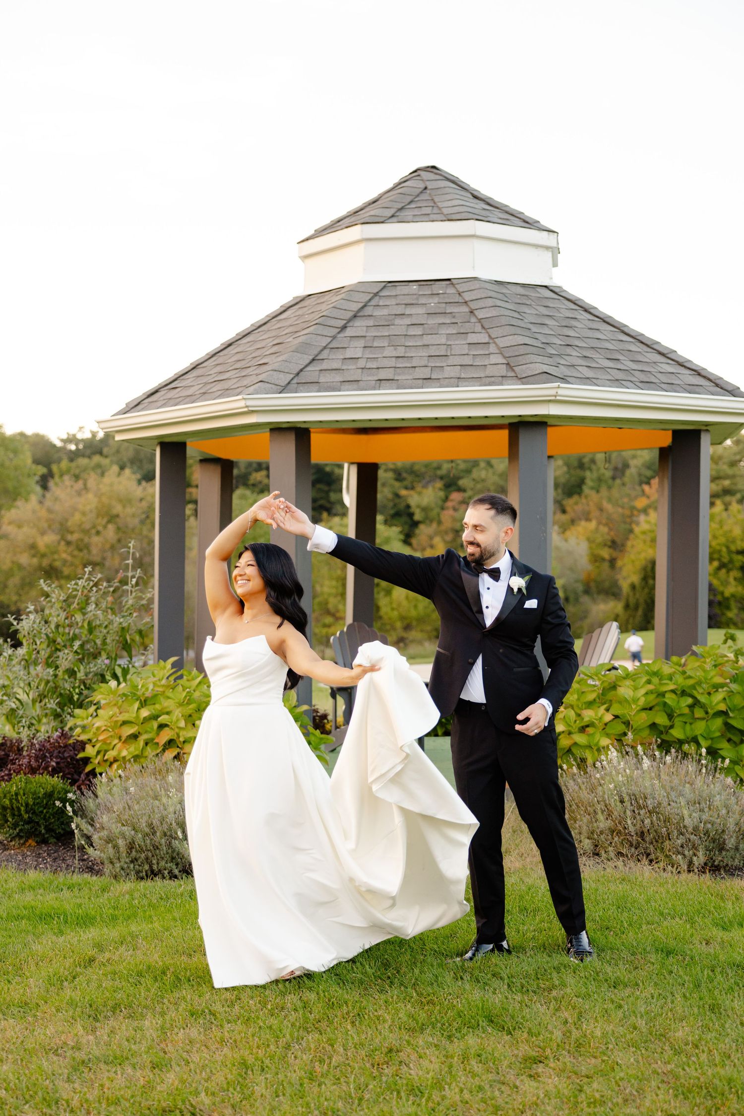 A joyful dancing moment between newlyweds outside a garden gazebo.