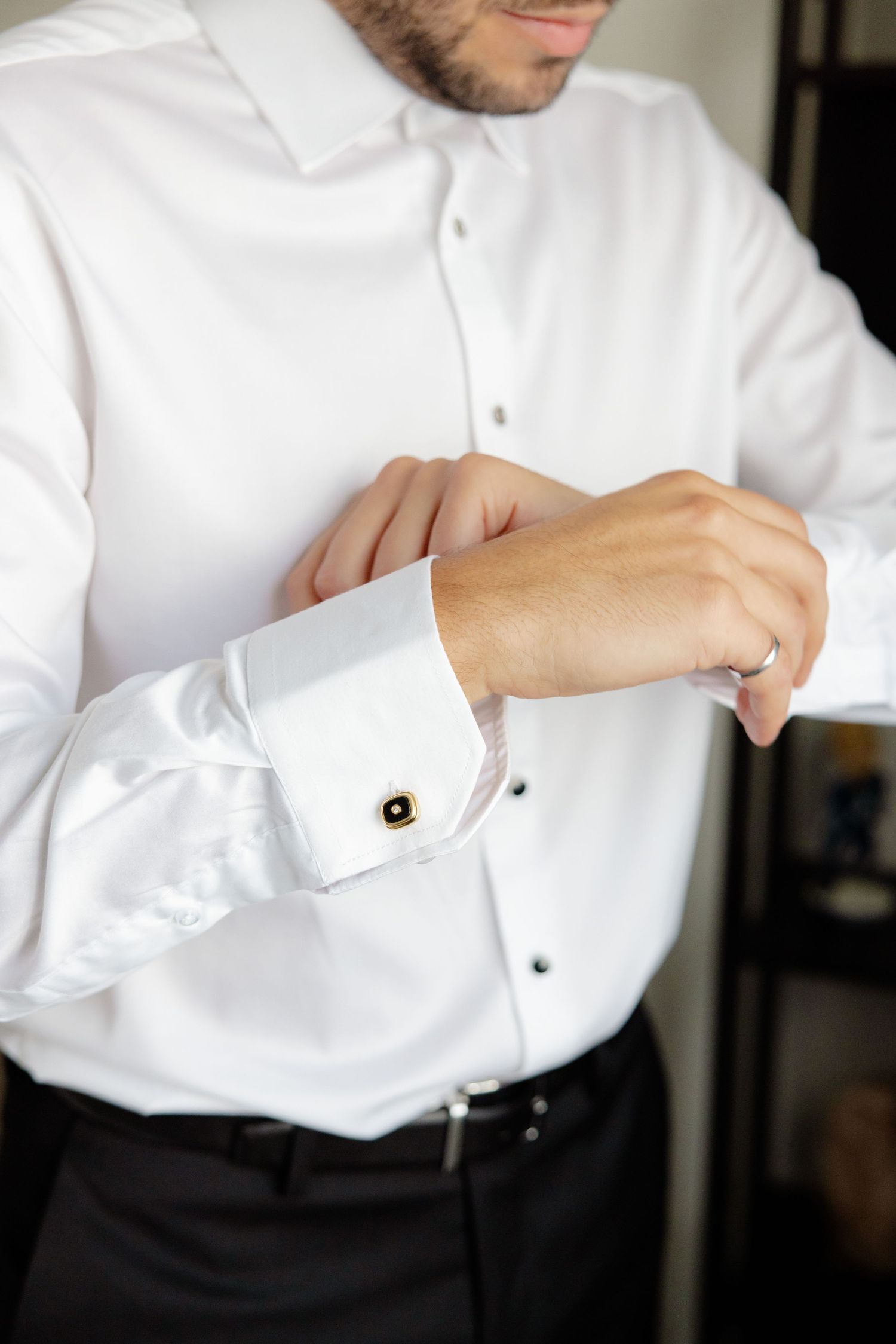 Two people in formal attire looking in mirror while adjusting bow tie.