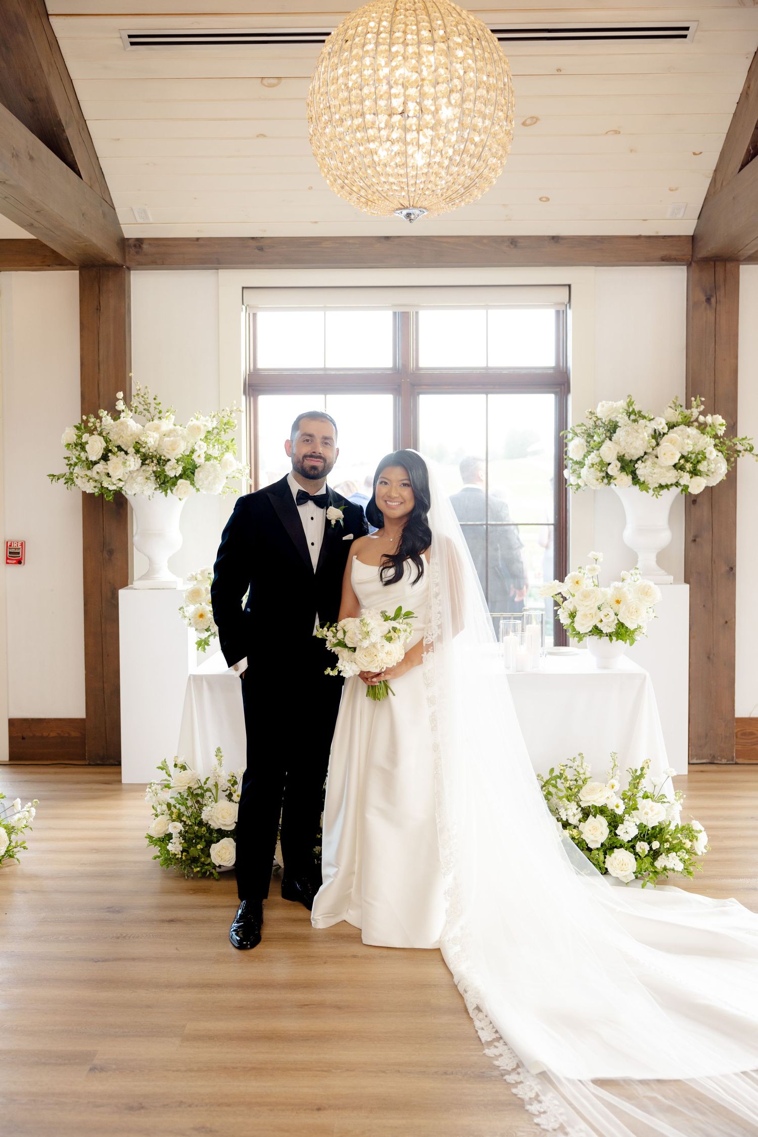 Luxurious wedding venue with crystal chandelier and white floral arrangements creating an elegant backdrop.