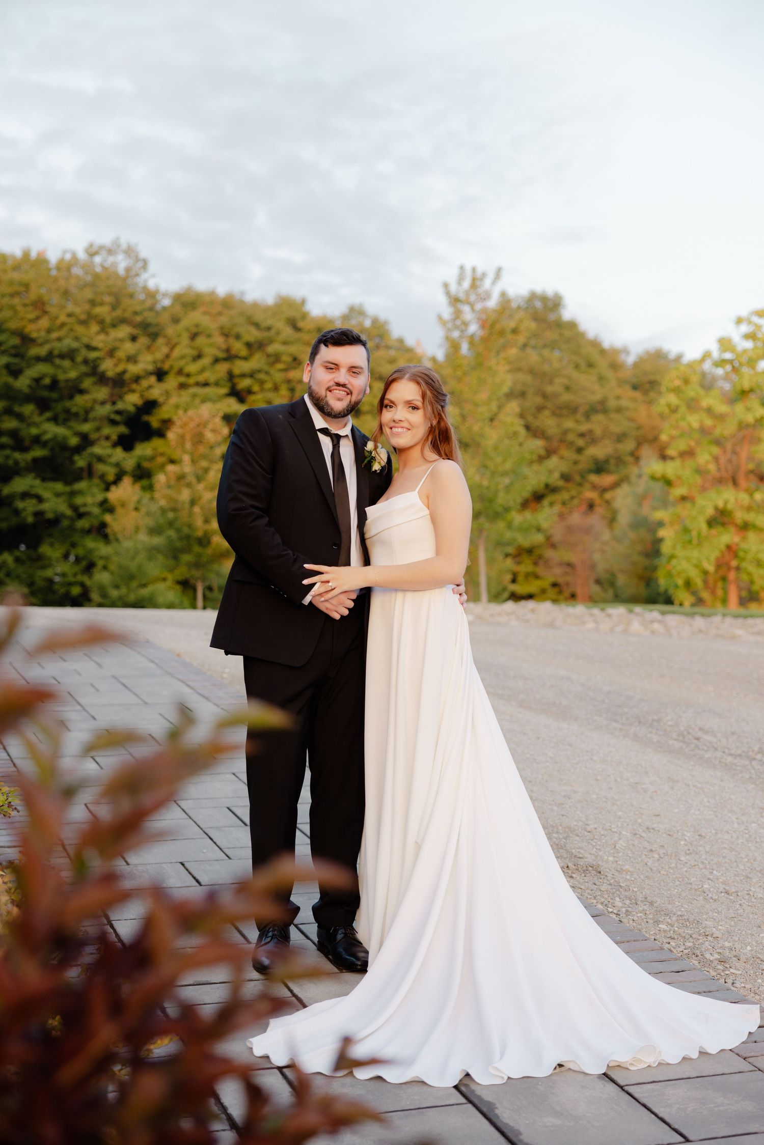 Elegant wedding portrait featuring couple in formal attire against autumn landscape.