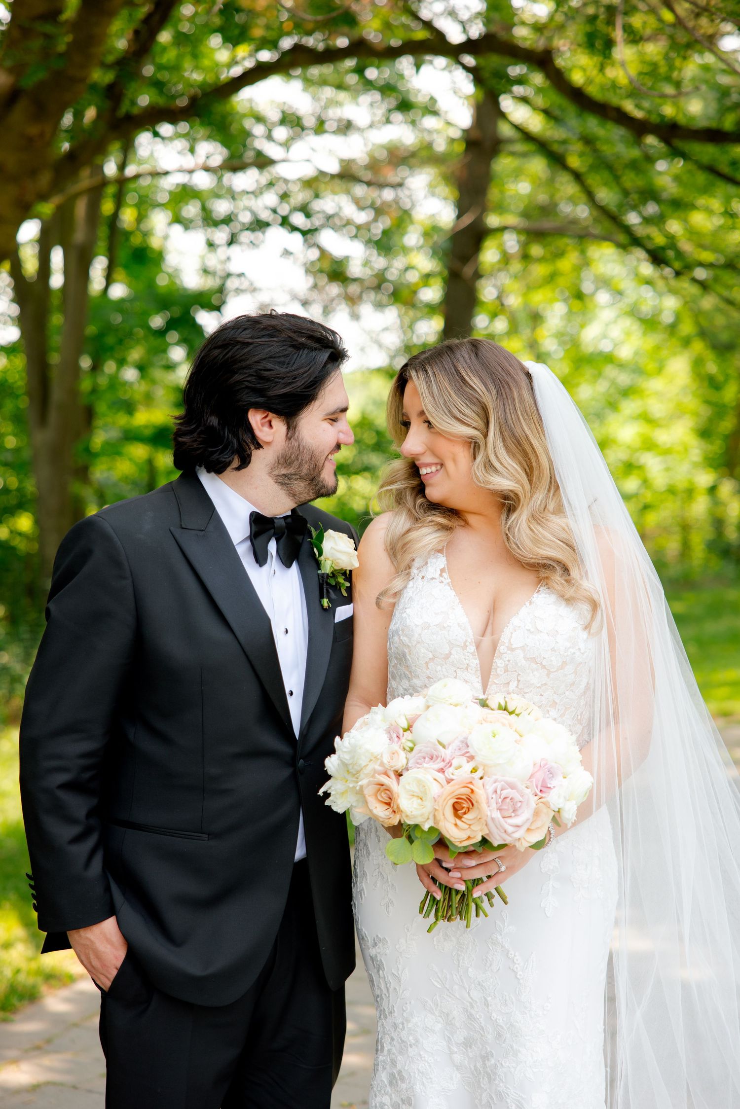 A couple shares an intimate moment during their wedding photoshoot in a sunlit garden setting.