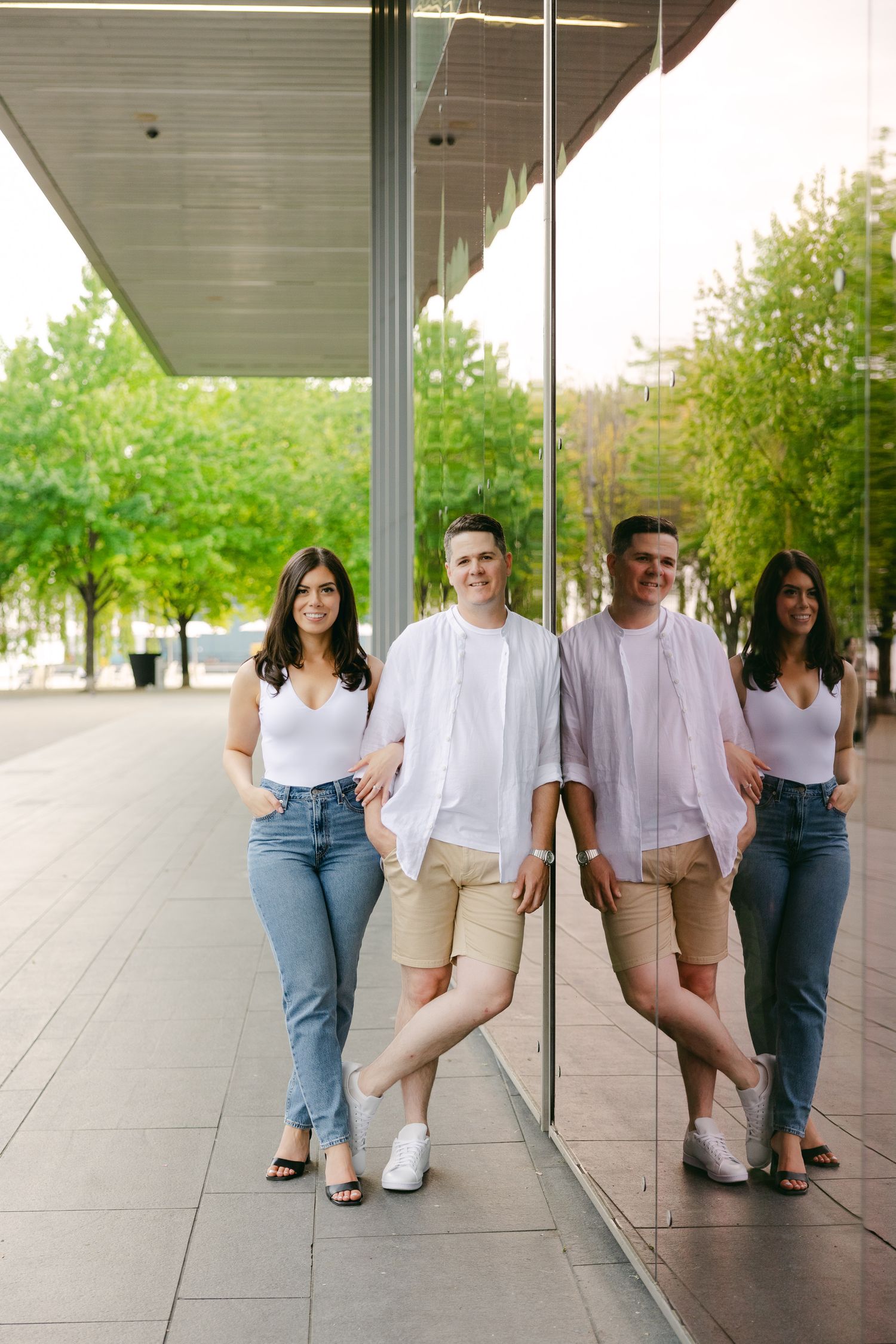 Two couples pose together in a covered walkway while dressed in casual summer attire.