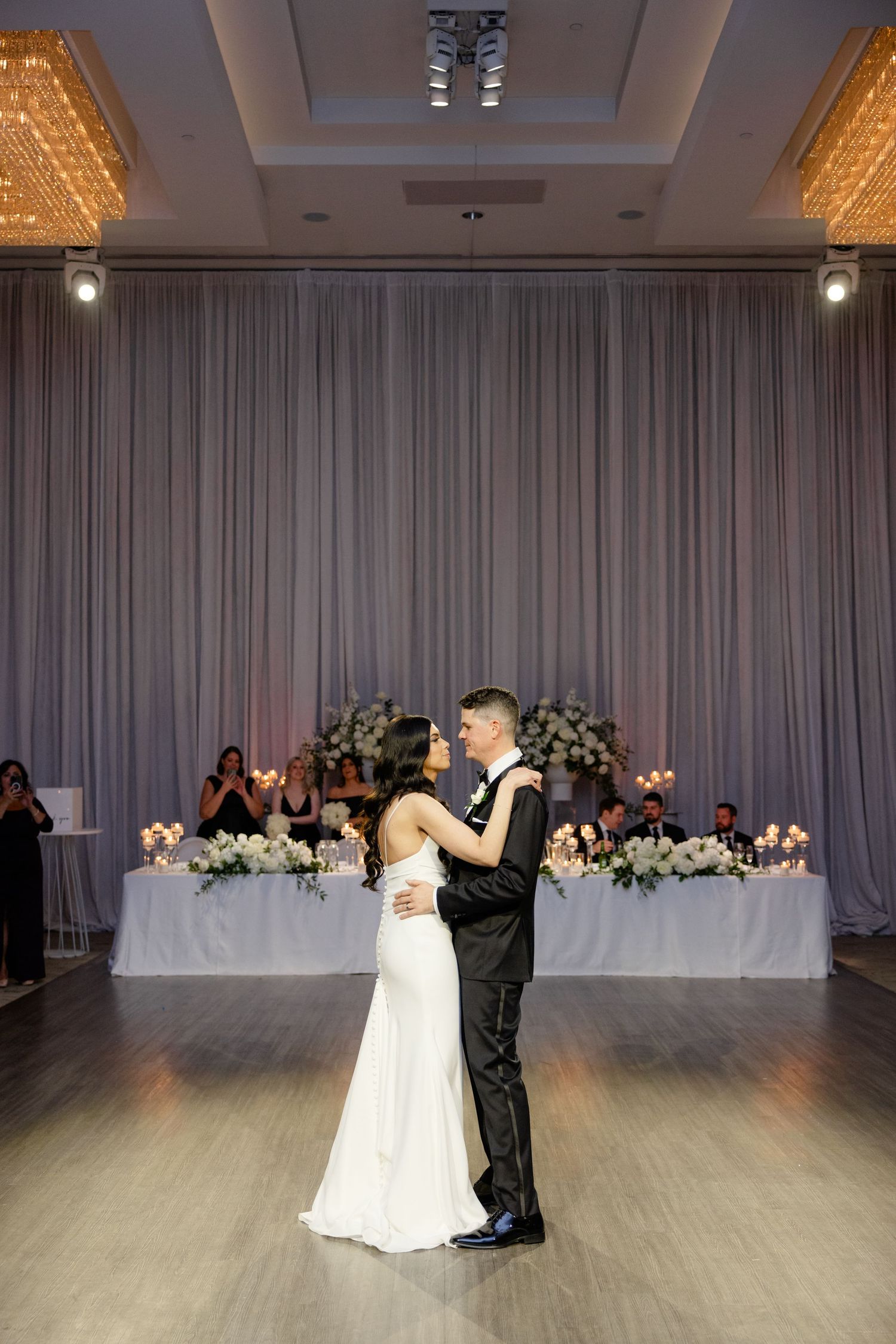 Couple shares romantic first dance moment in beautifully lit reception venue.