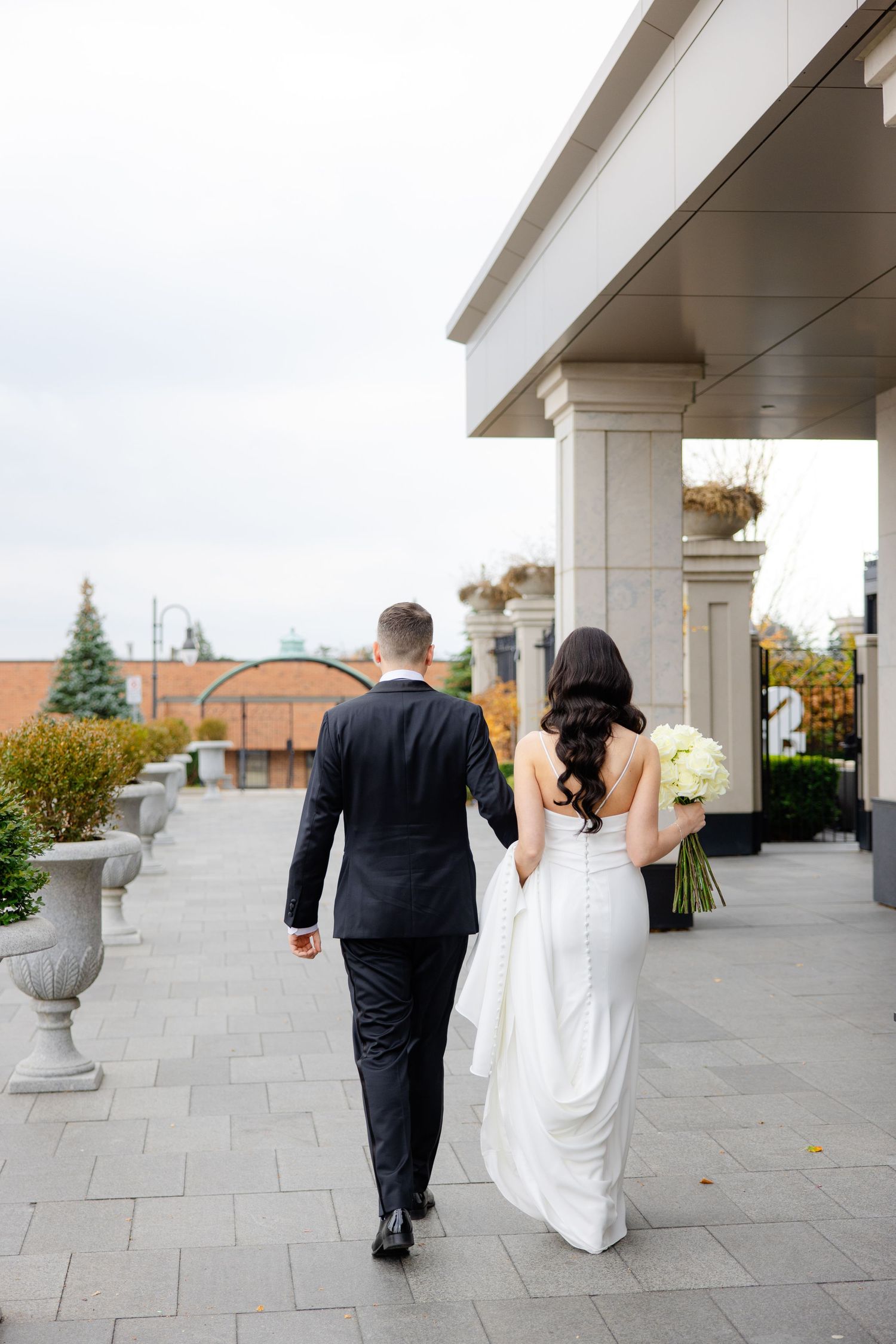 Newlyweds walk together along an elegant columned terrace on their wedding day.