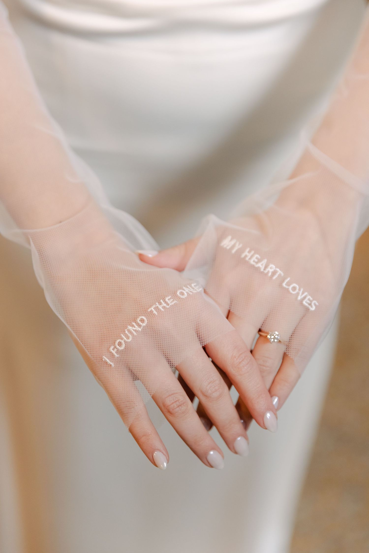 Close-up of wedding vows embroidered on sheer fabric with engagement ring detail.