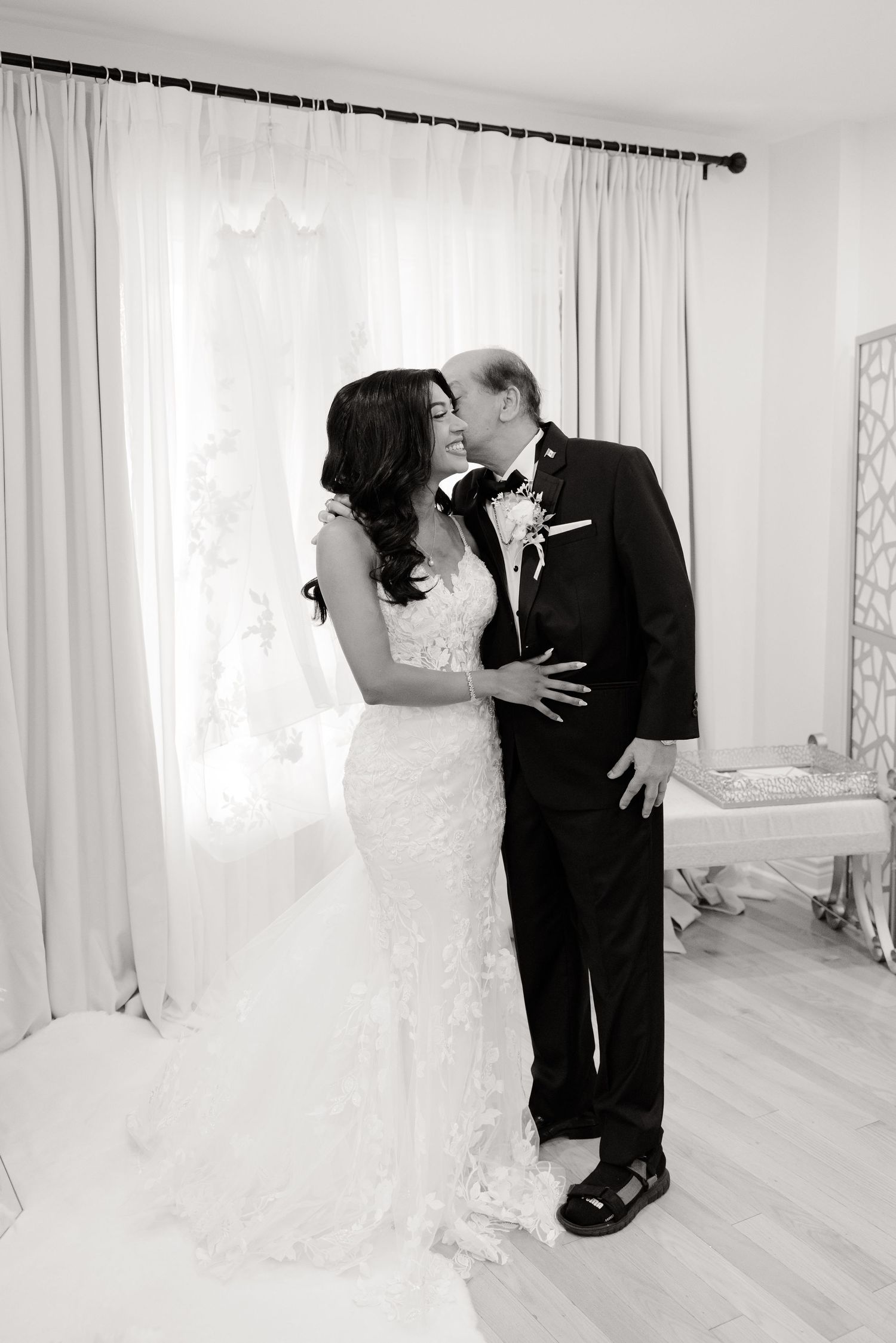 Black and white emotional wedding photograph capturing a heartfelt embrace in an elegant setting.