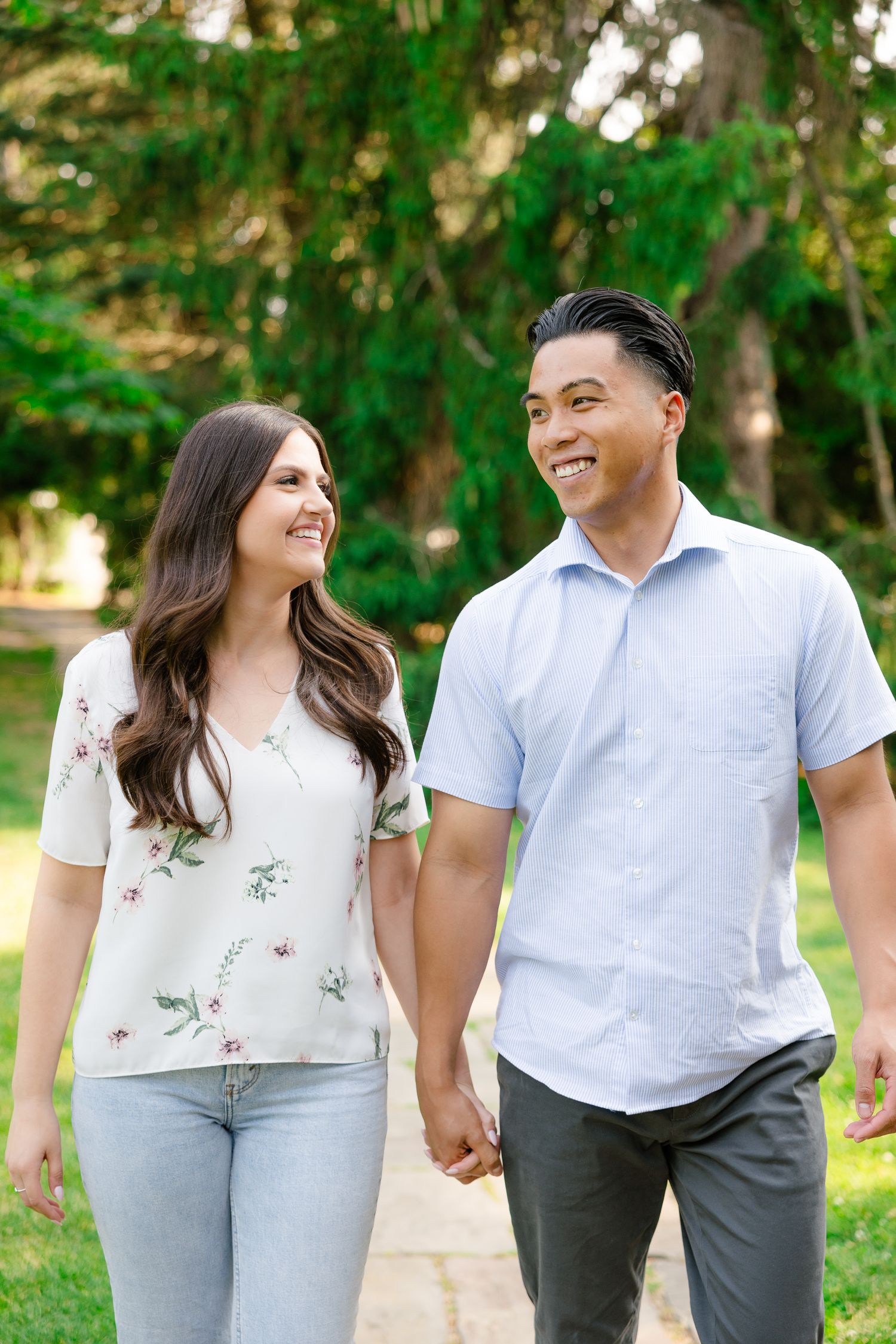 A couple shares a joyful moment while walking hand-in-hand along a garden pathway.
