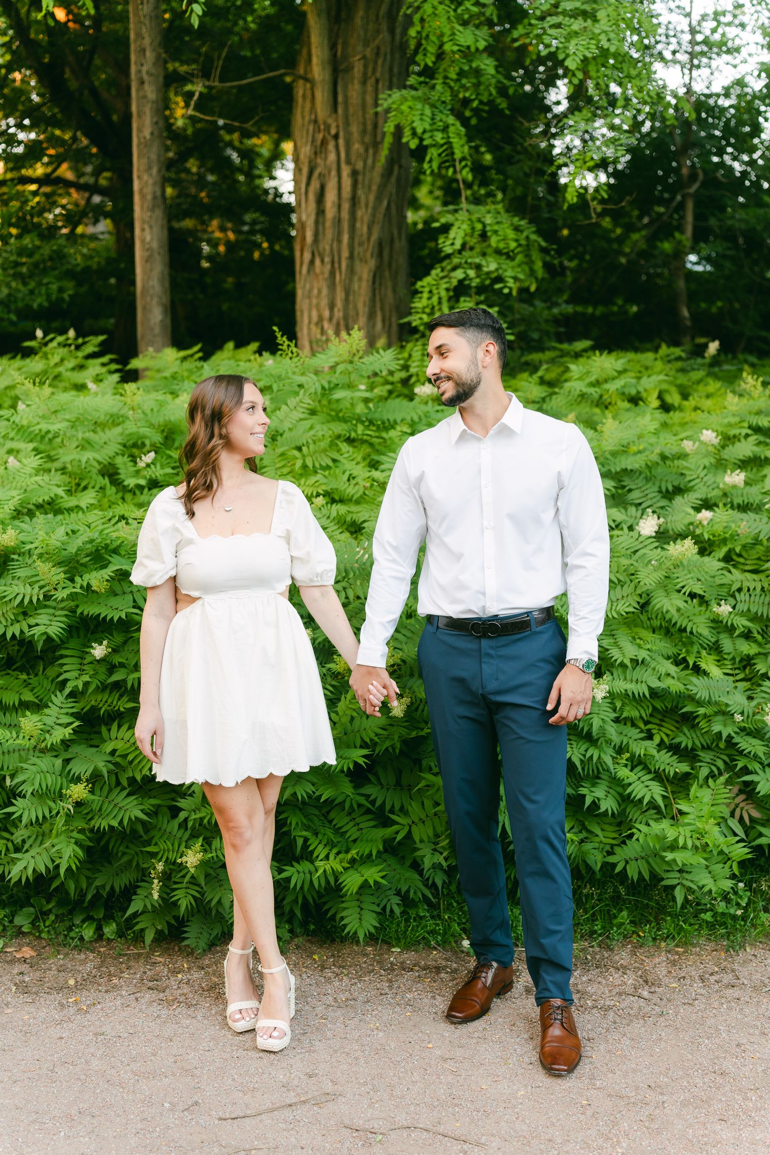 Couple sharing a moment together among tall ferns in garden setting.