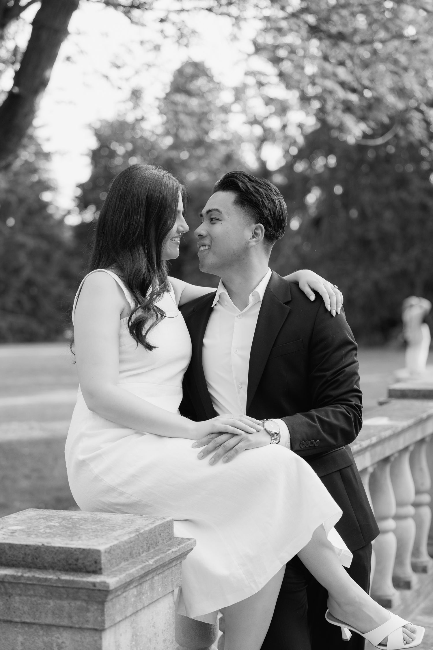 Black and white portrait of couple sharing romantic moment on stone balustrade.