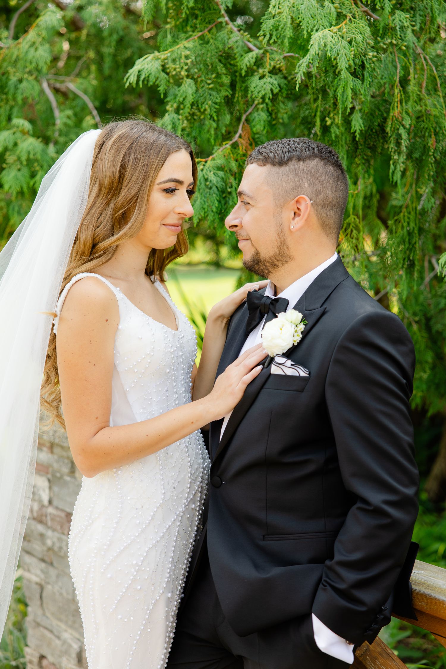 Intimate wedding moment captured under lush green trees in a garden setting.