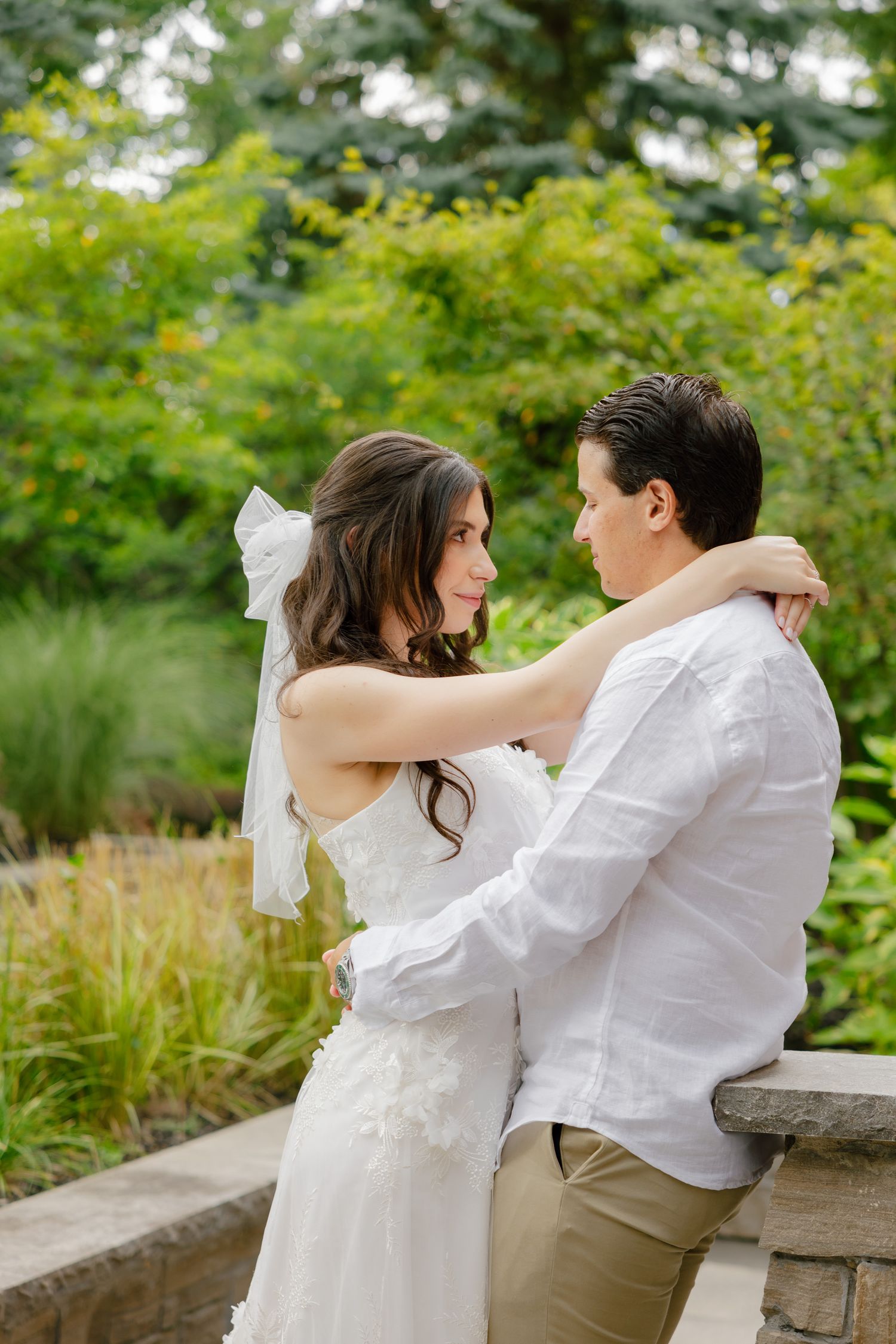 Candid wedding moment captured as couple embraces in garden setting.