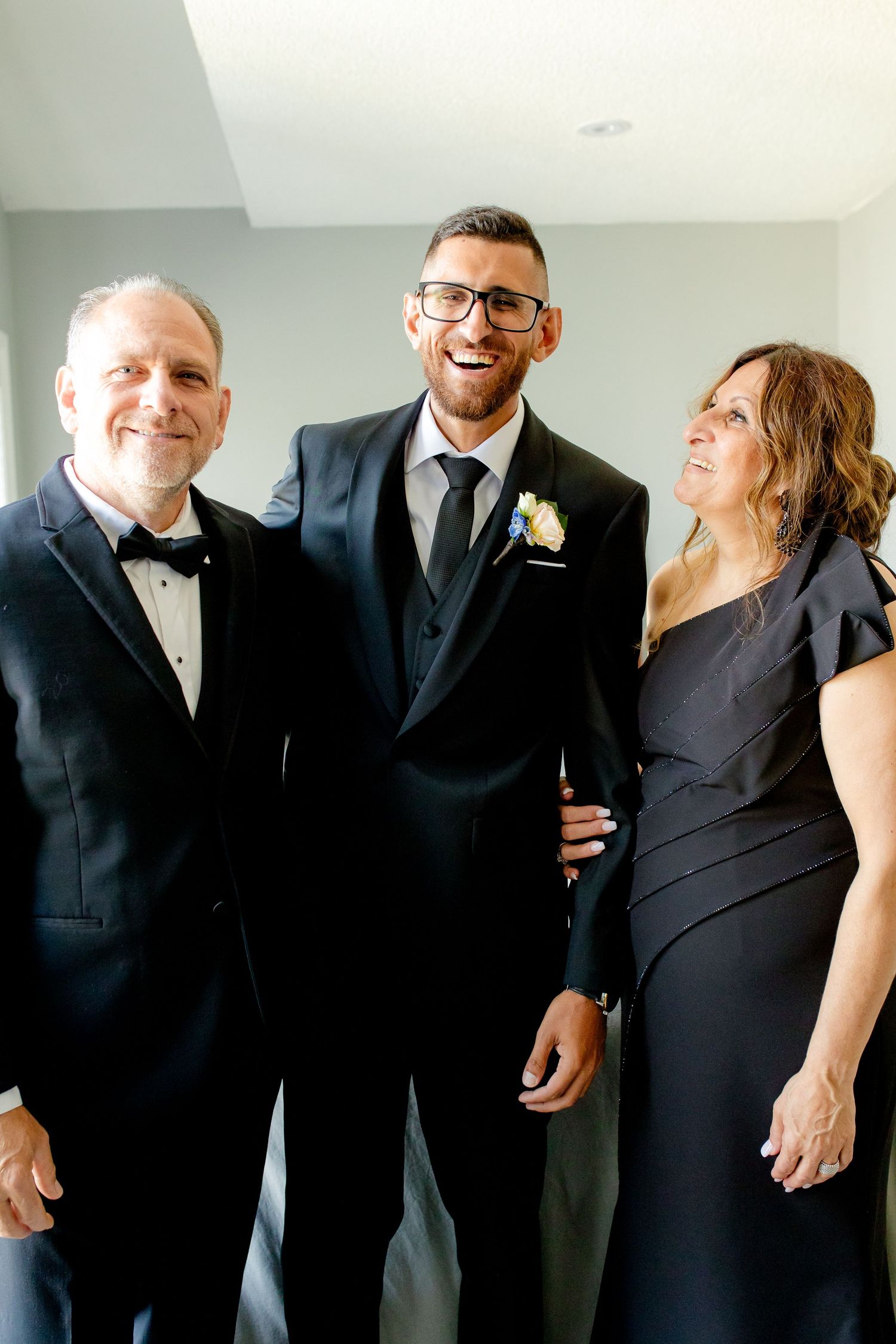 Three people in formal attire share a joyful moment together.
