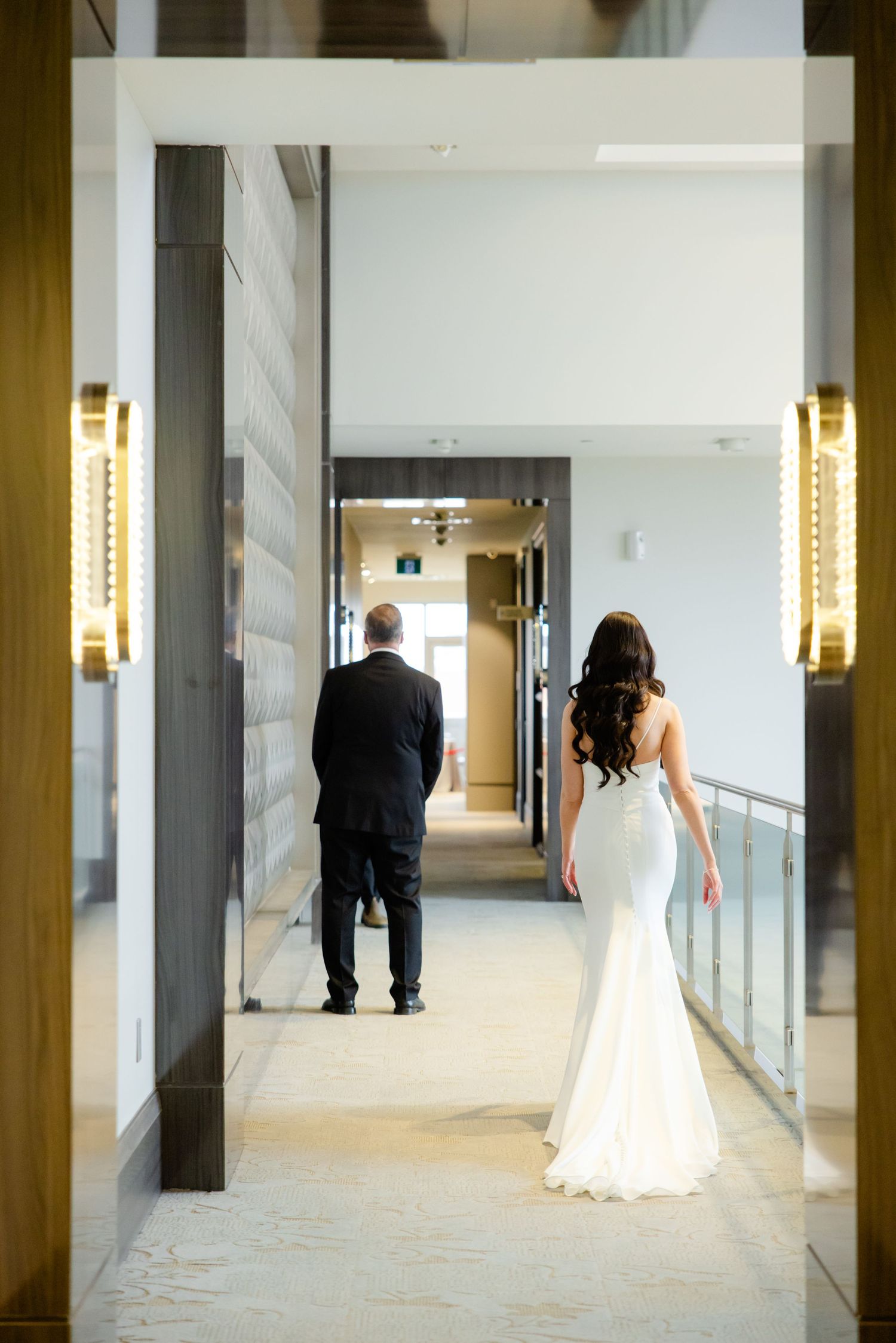 Wedding day corridor scene with elegant lighting and formal attire.