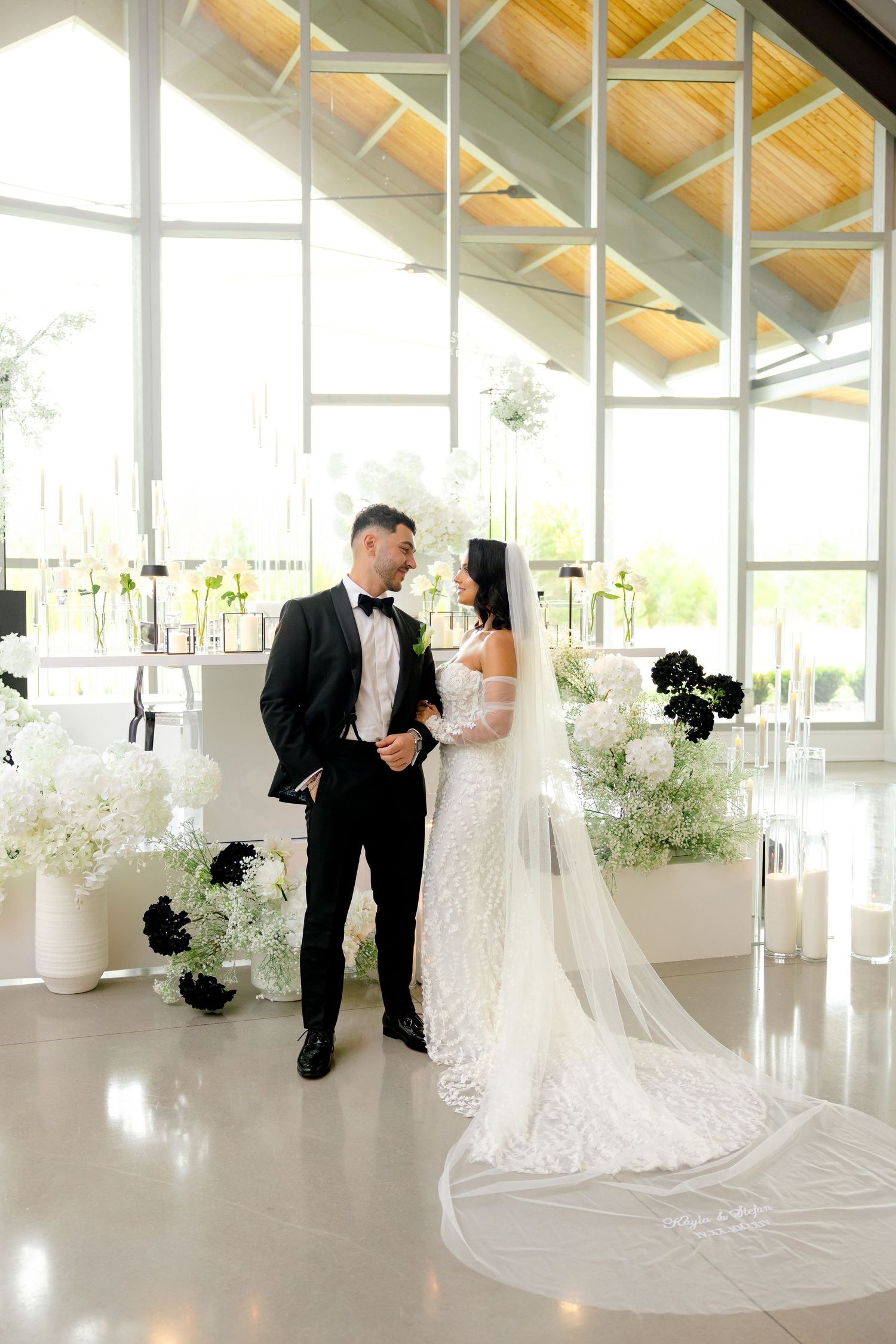 Elegant wedding venue with wooden beam ceiling and floor-to-ceiling windows filled with natural light.