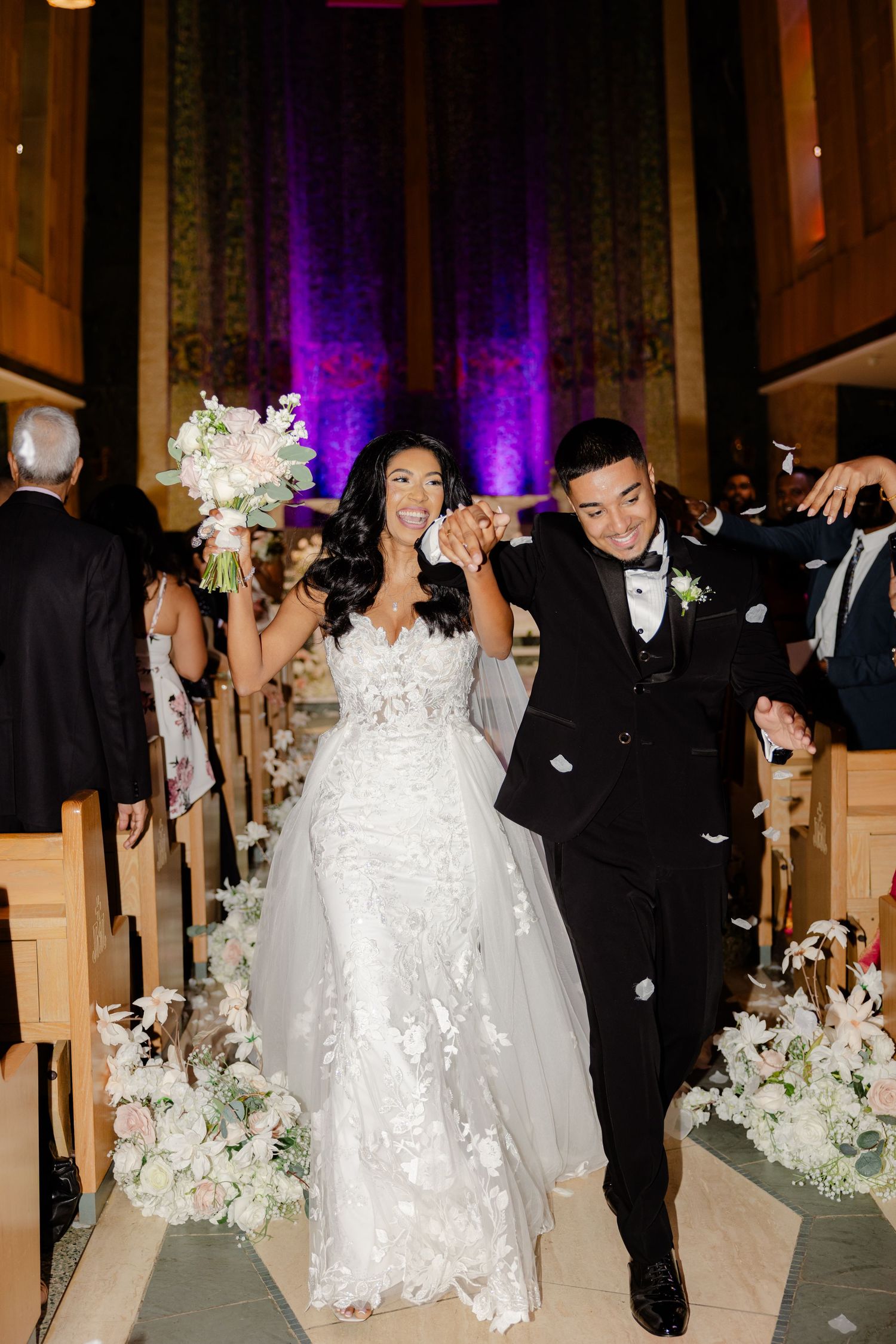 Newlyweds walk down the church aisle while guests celebrate their union.