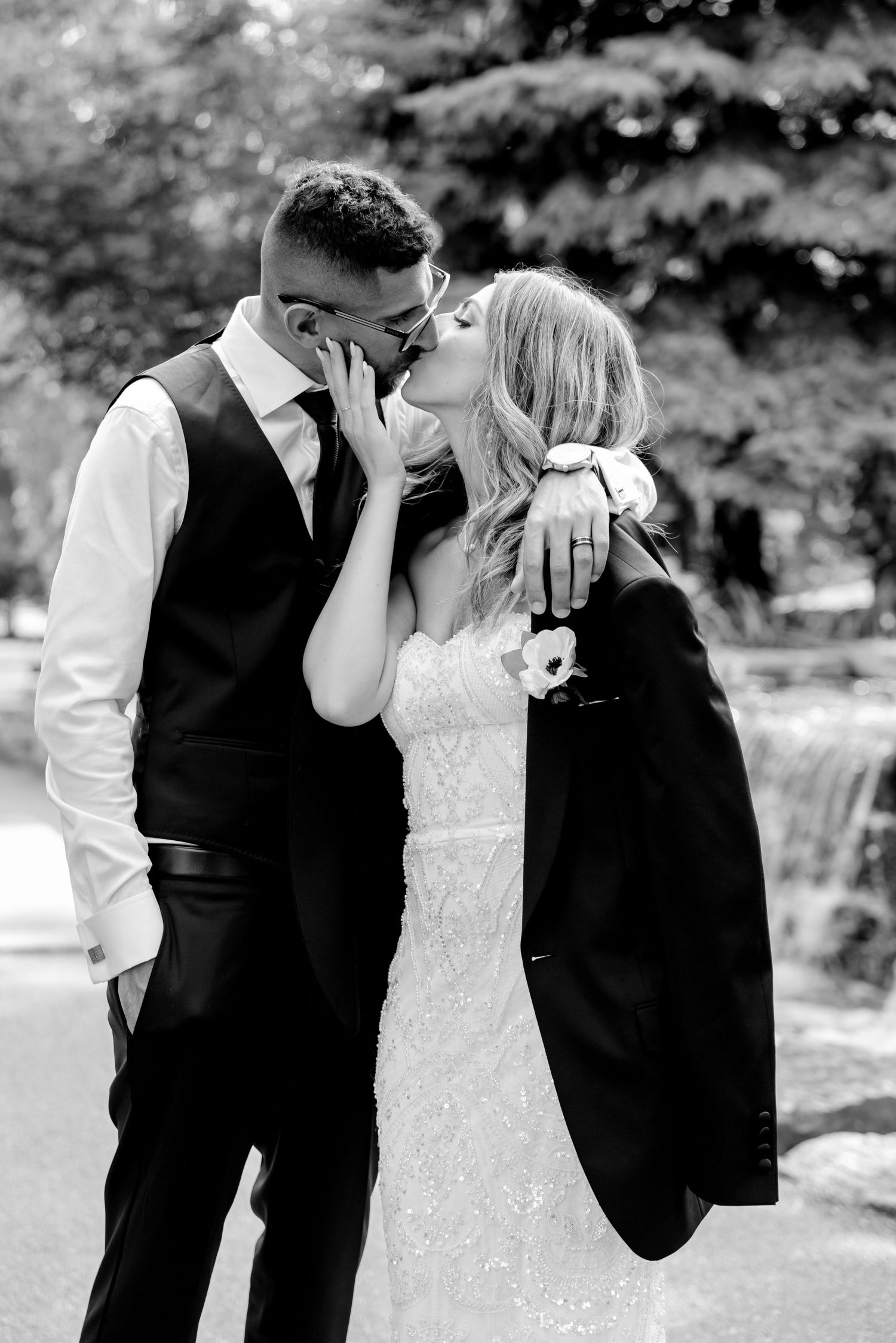Black and white intimate portrait of couple by garden waterfall.