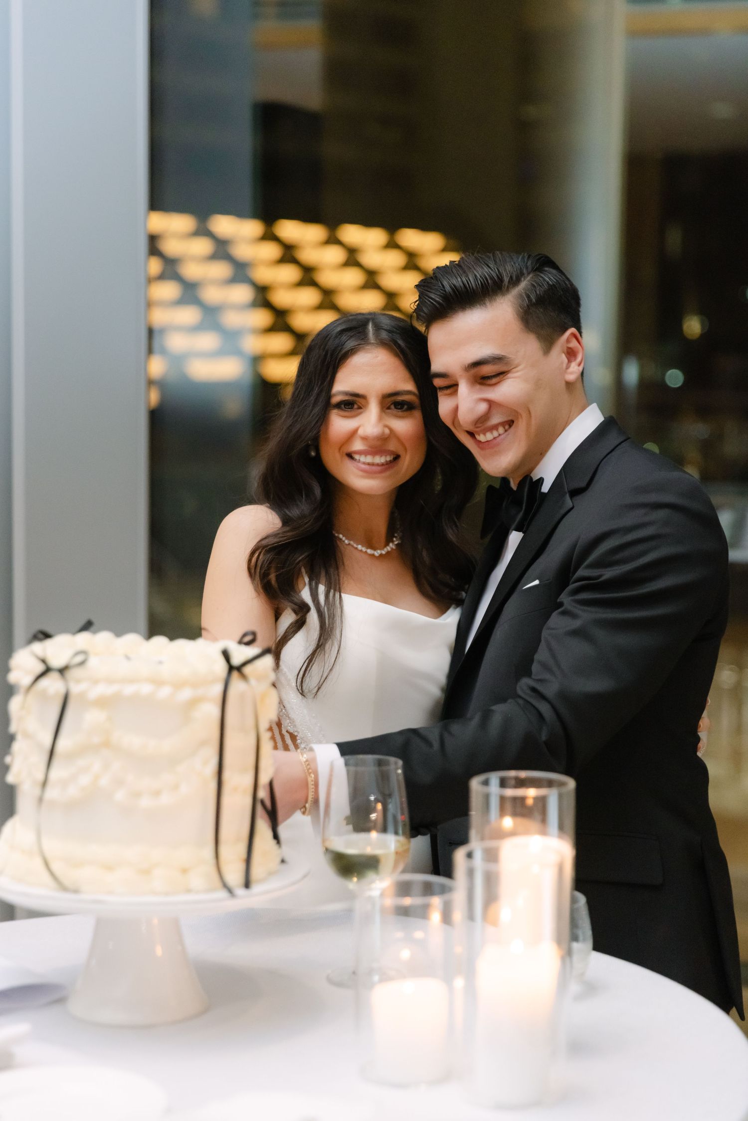 Happy couple sharing a joyful moment beside their wedding cake at the reception.