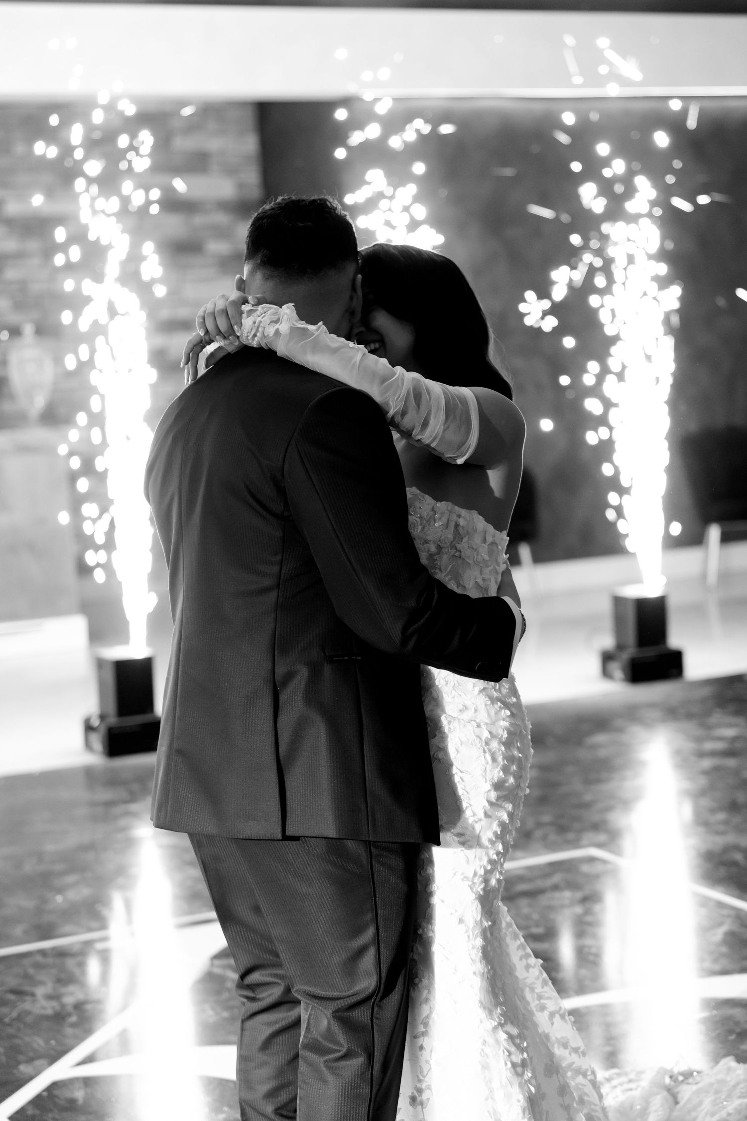 Romantic dance moment captured in black and white with sparkling fountains in the background.