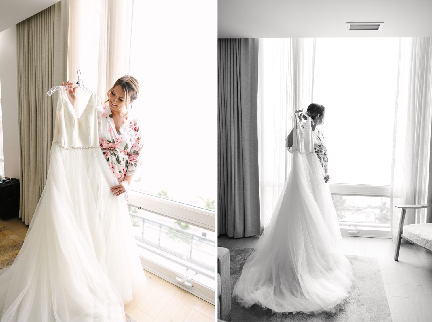 Bride admiring white wedding dress hanging by window in hotel room.
