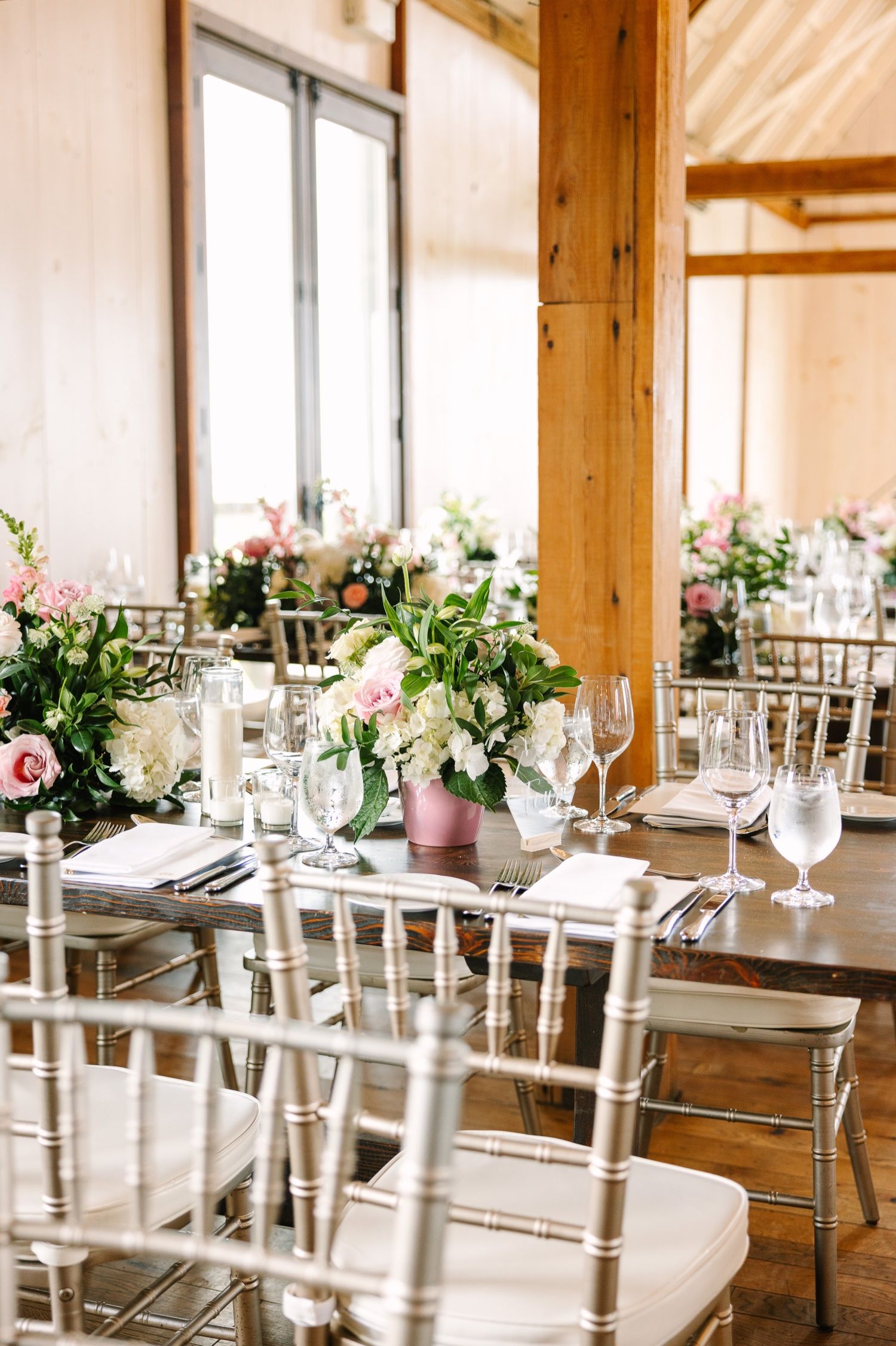 Wedding reception table with silver chiavari chairs and romantic floral centerpieces.