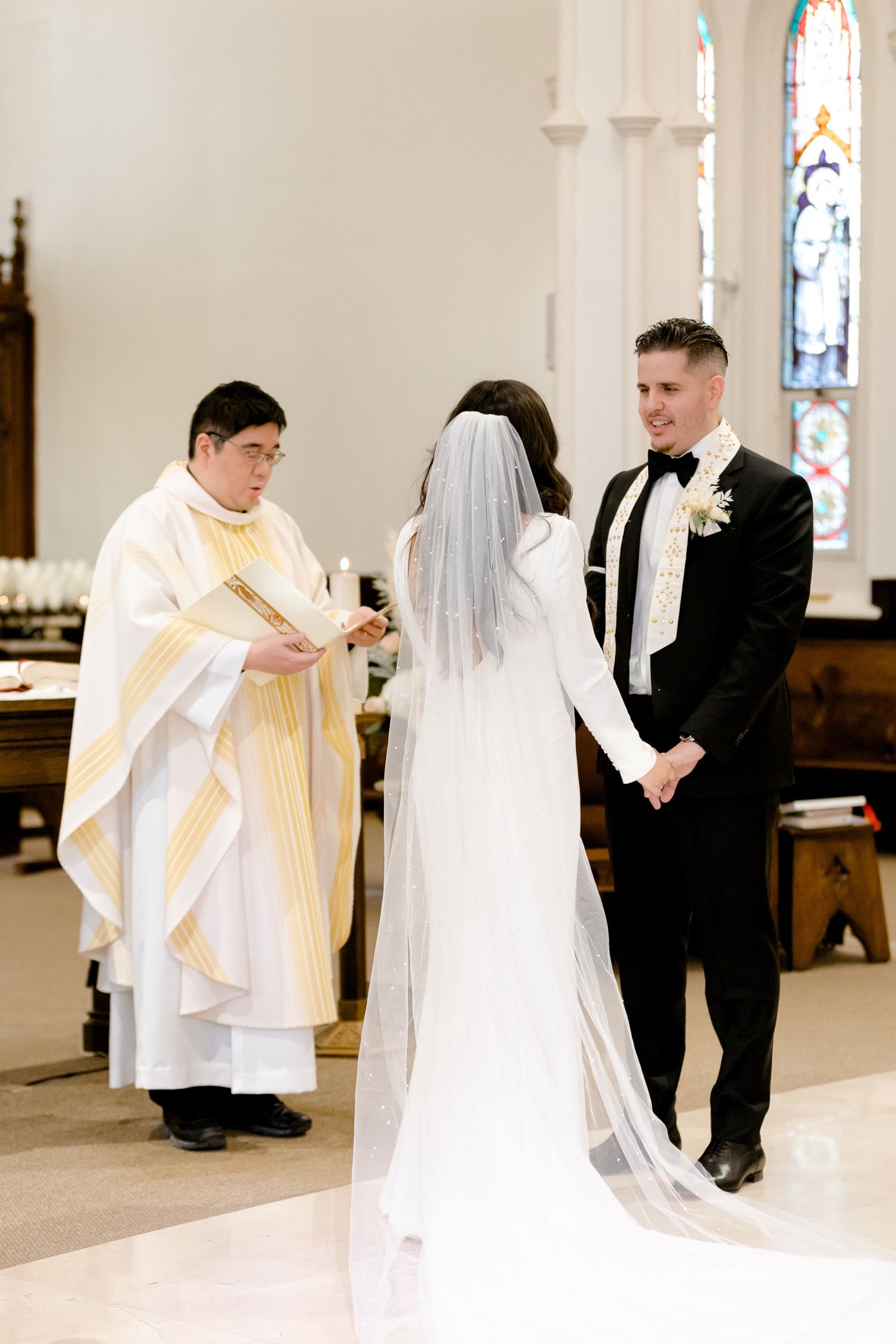A wedding ceremony in progress inside a beautiful church with traditional architecture and stained glass windows.