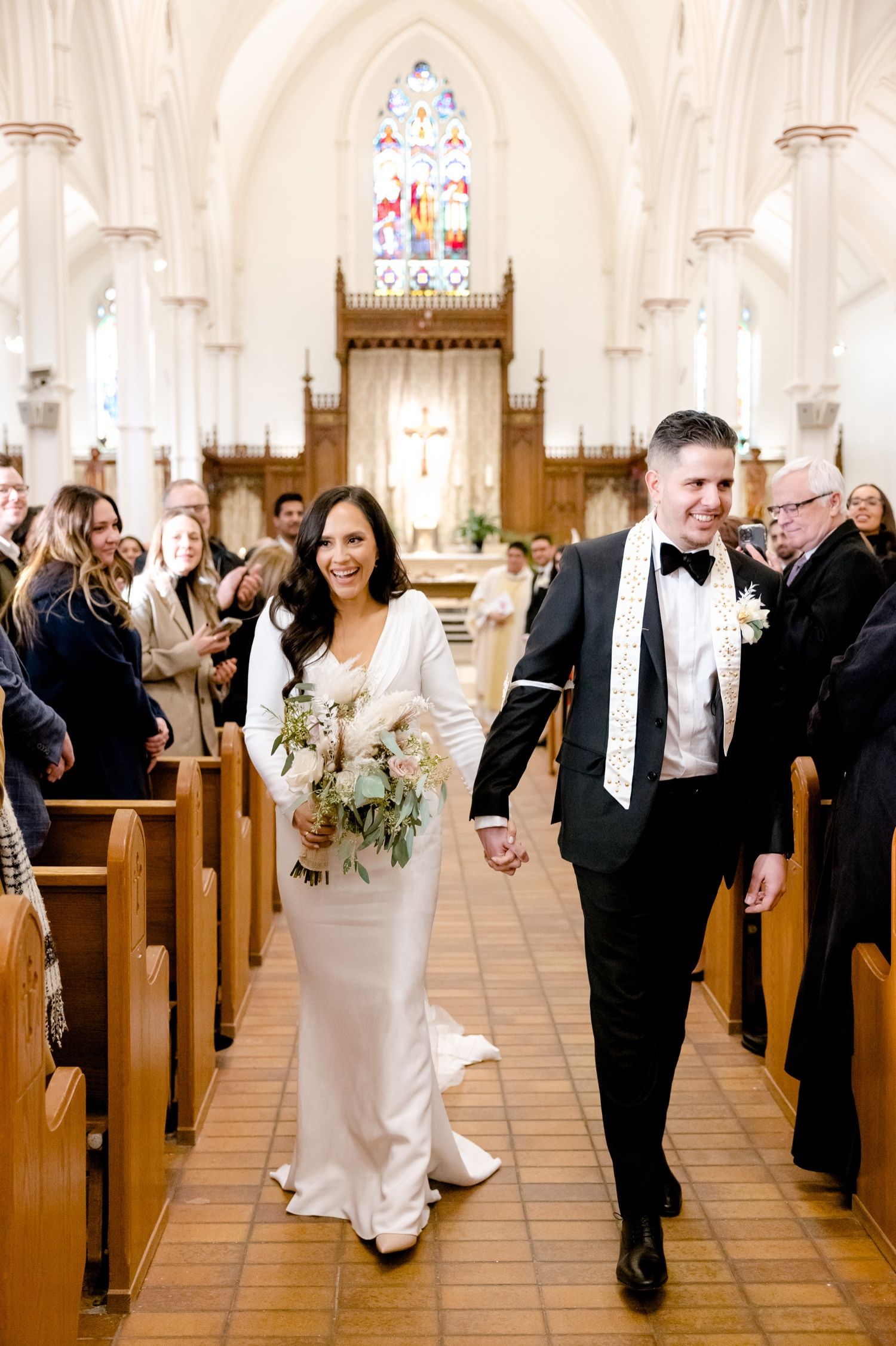 A happy couple proceeding down the church aisle while guests celebrate their union.