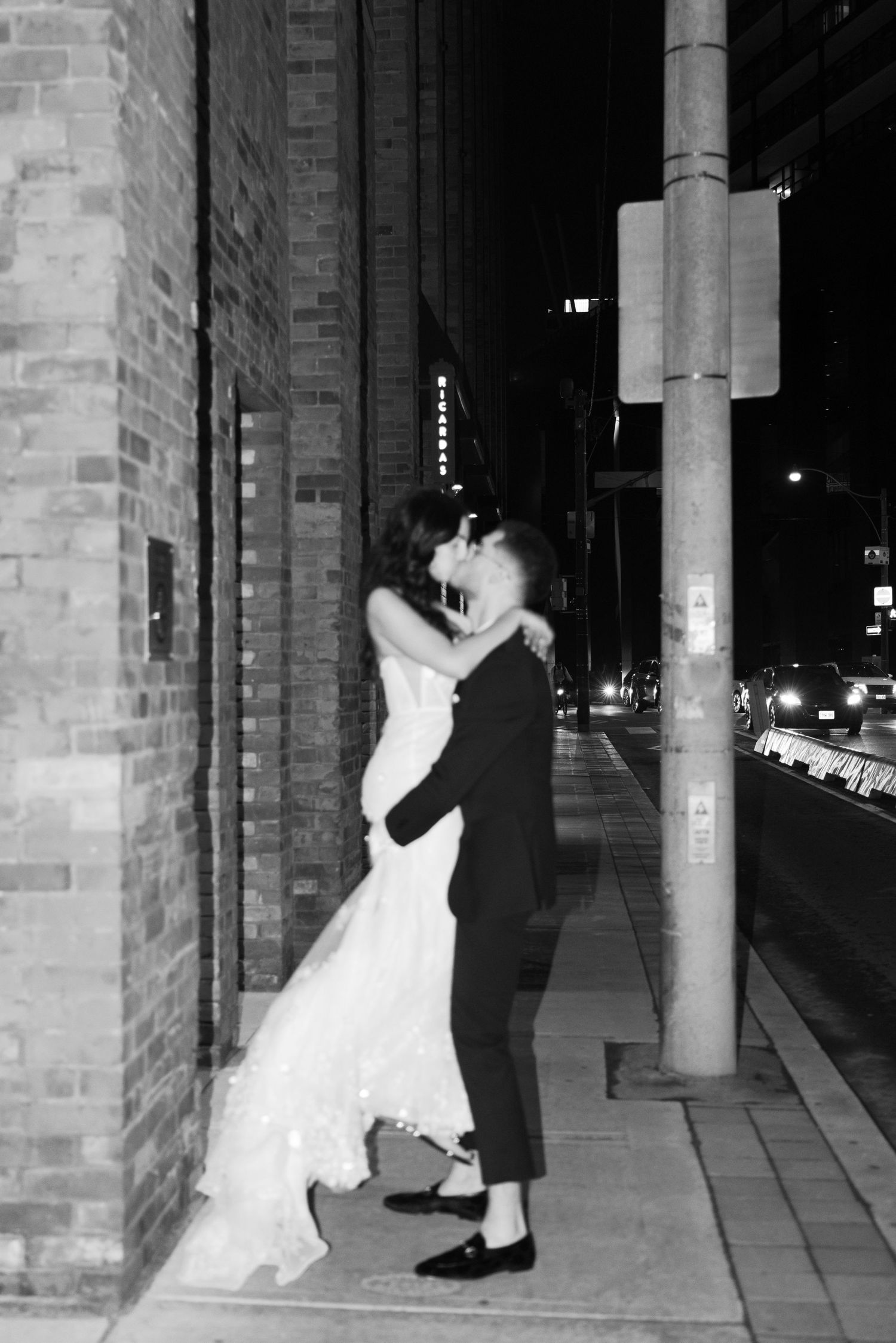 Black and white portrait of newlyweds sharing an intimate moment on city sidewalk.