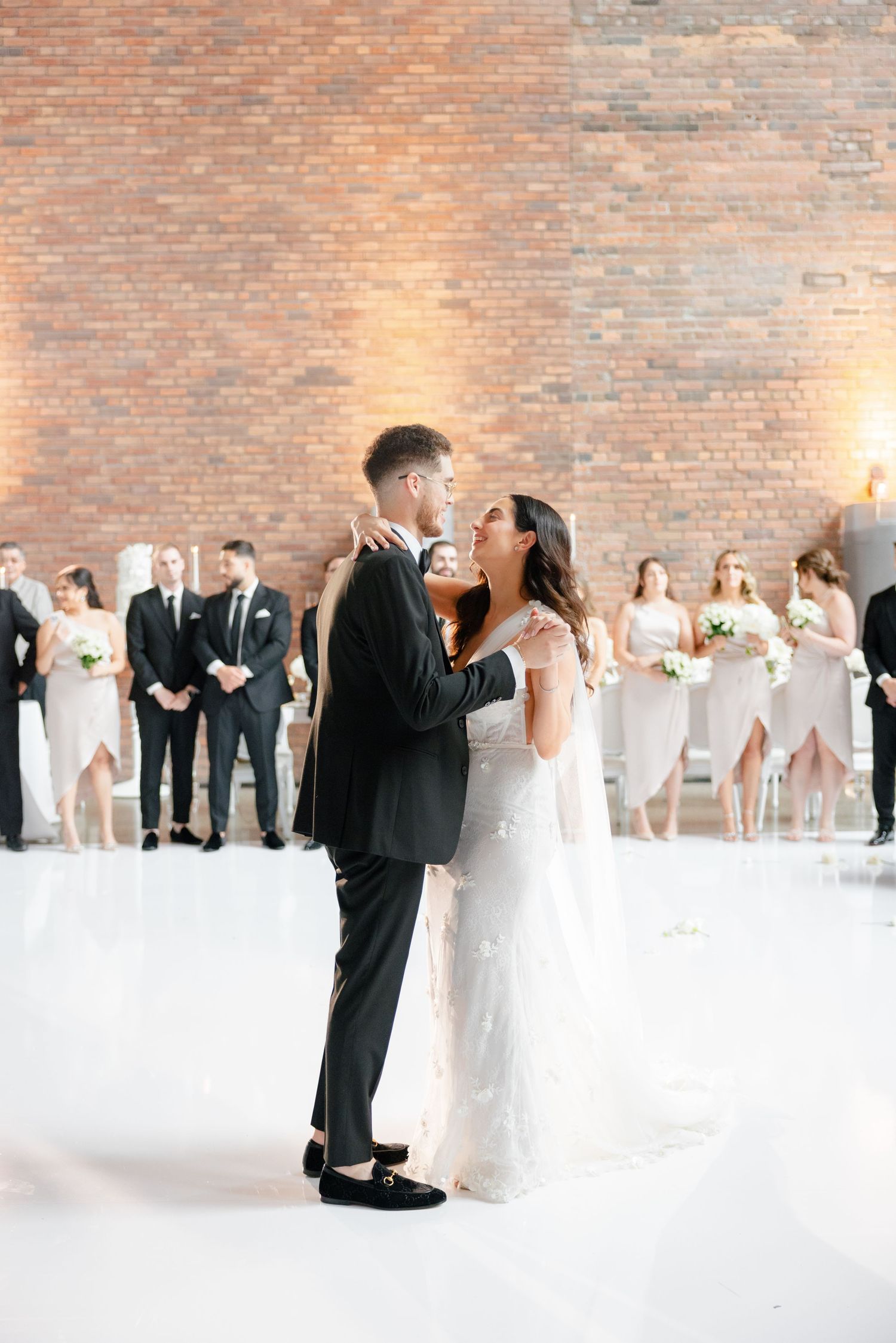 Wedding celebration in an industrial venue with exposed brick walls and modern white decor.