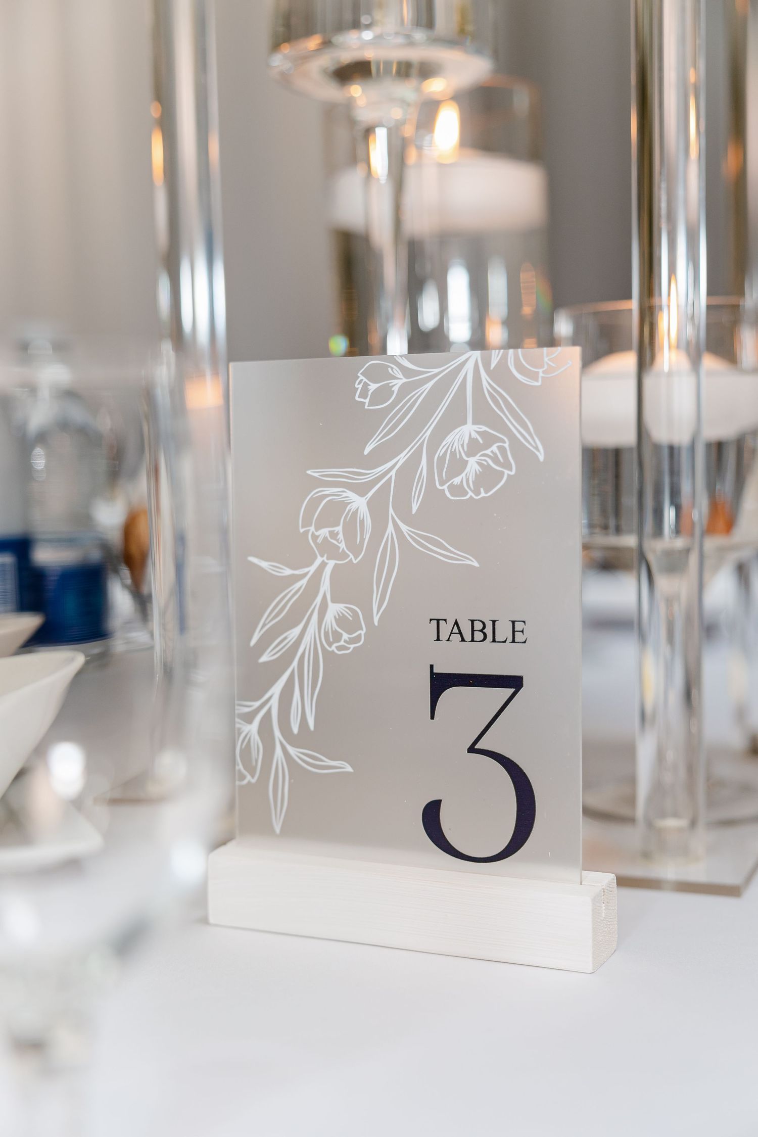 Elegant wedding table number card featuring floral design and number 3 in white and navy.