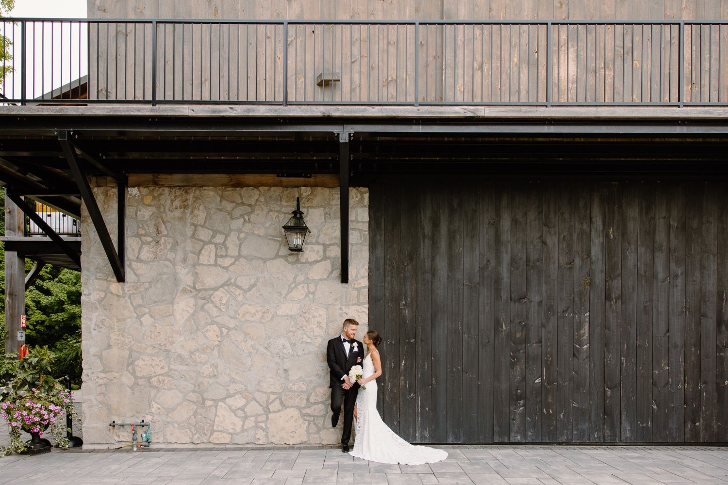 Romantic wedding portrait under balcony with stone and wood backdrop.