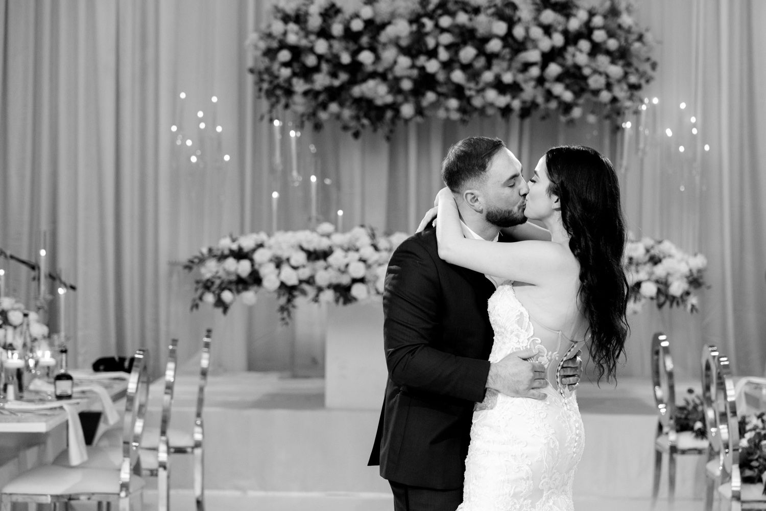 Romantic moment captured during a wedding ceremony with elegant floral arrangements in the background.