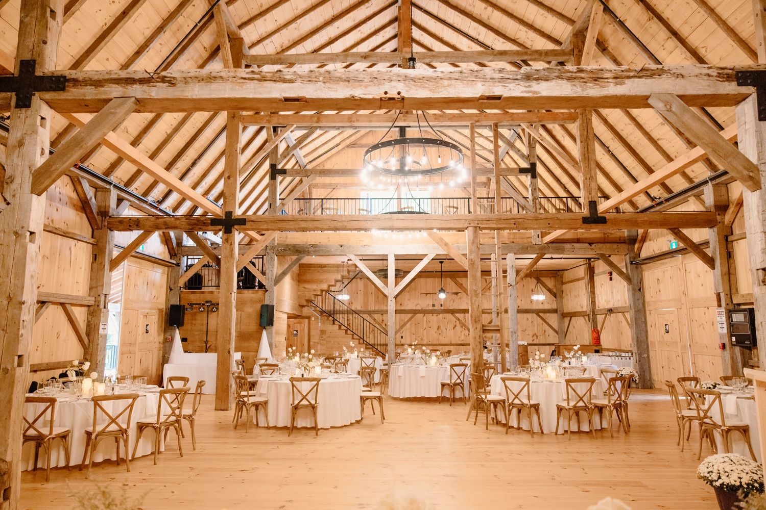 Rustic wooden barn reception venue with exposed beams and elegant table settings.