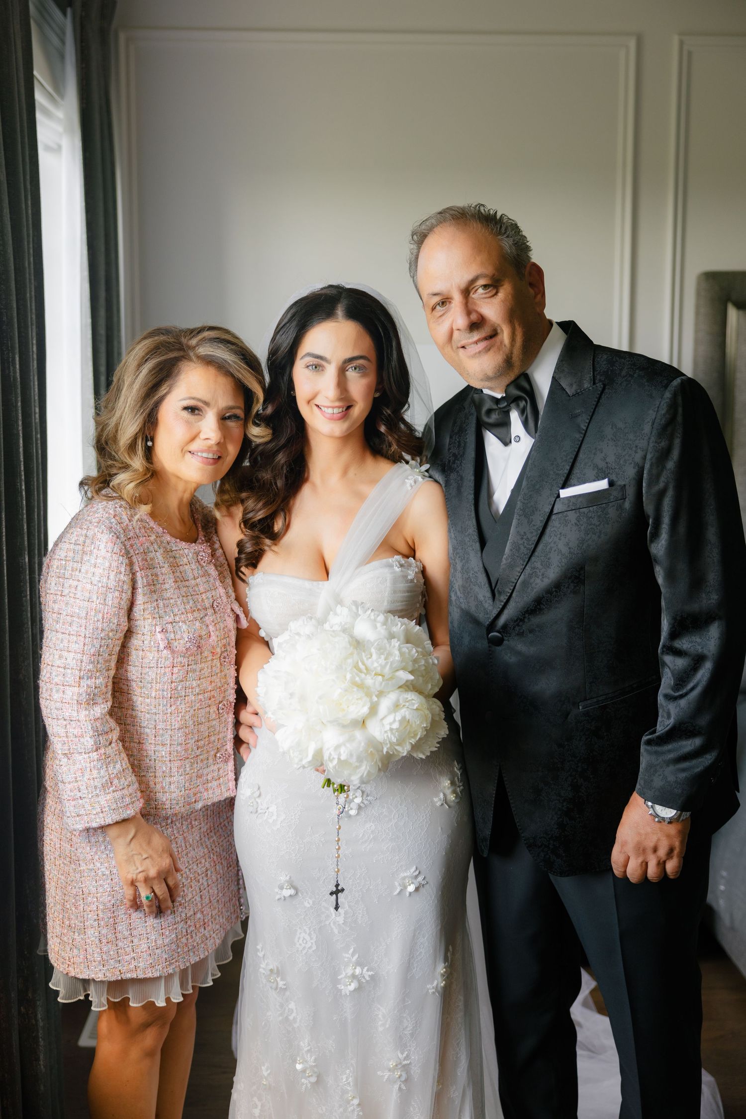 An elegant wedding portrait beside large windows with natural light streaming in.