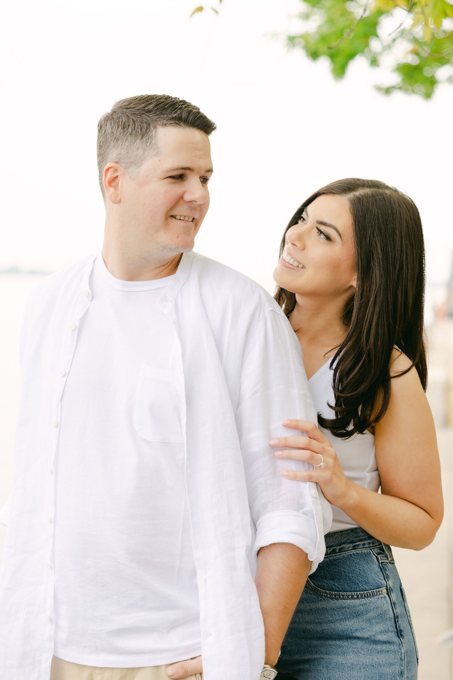 A candid moment between a couple in casual attire by the waterfront.