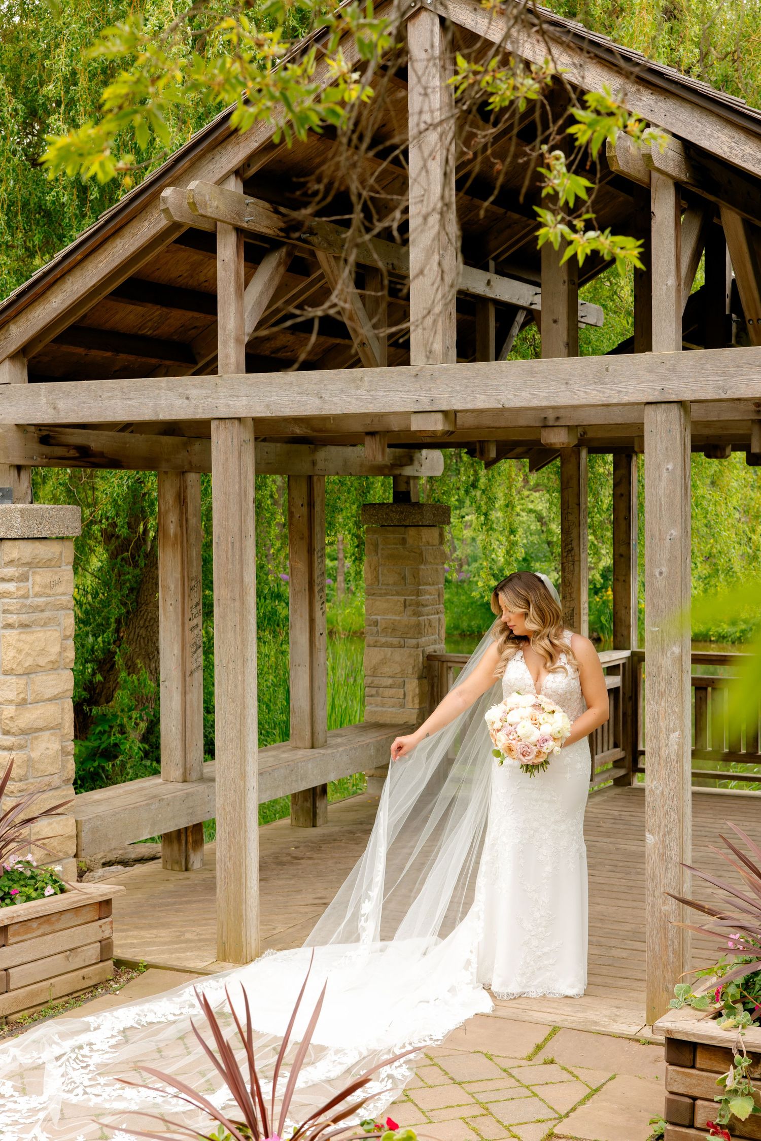 A stunning wedding dress with flowing veil captured in a garden gazebo setting.