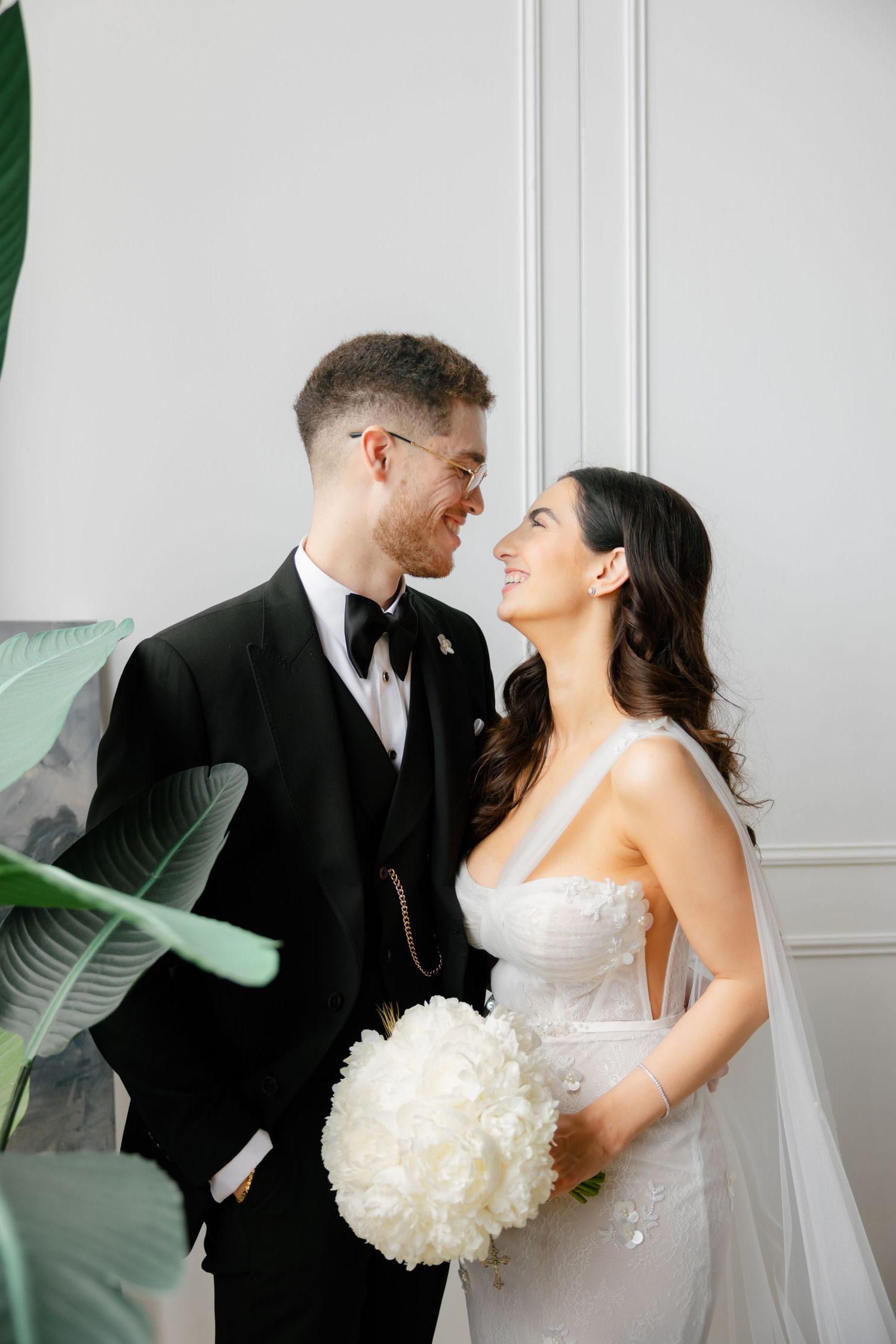Joyful wedding couple shares loving moment surrounded by tropical greenery.