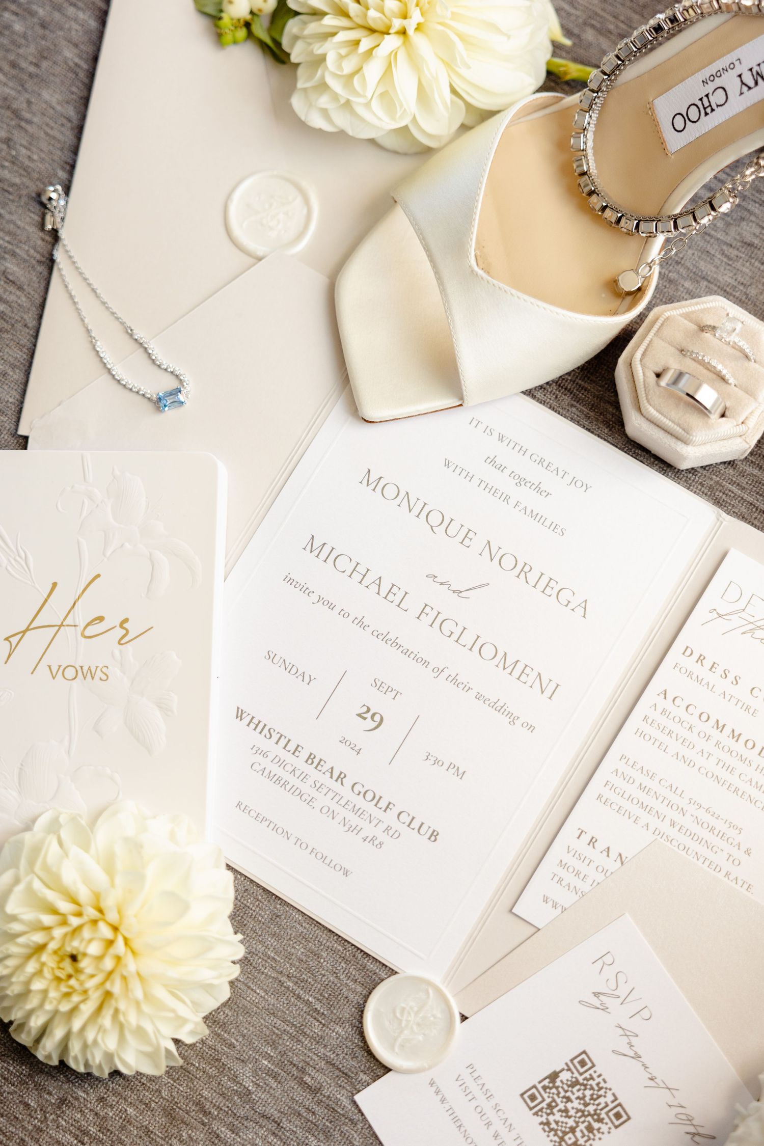 Wedding stationery flatlay with white invitation suite, Jimmy Choo heels and dahlia flowers.
