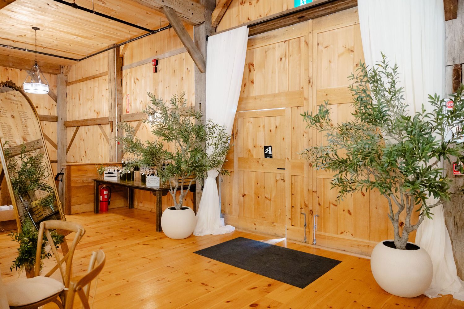 Rustic barn venue interior with wood walls and potted olive trees.