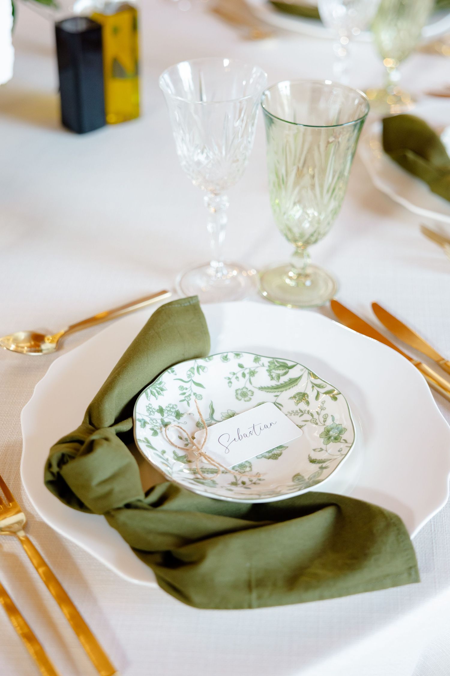Elegant table setting with sage napkin, floral plate, and vintage glassware.