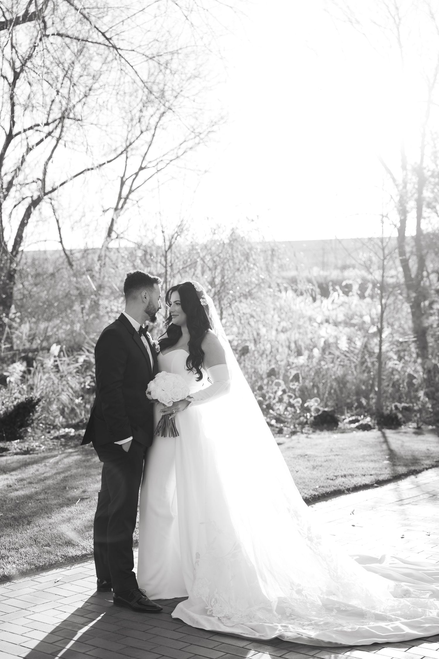 Black and white portrait of wedding couple surrounded by winter trees.