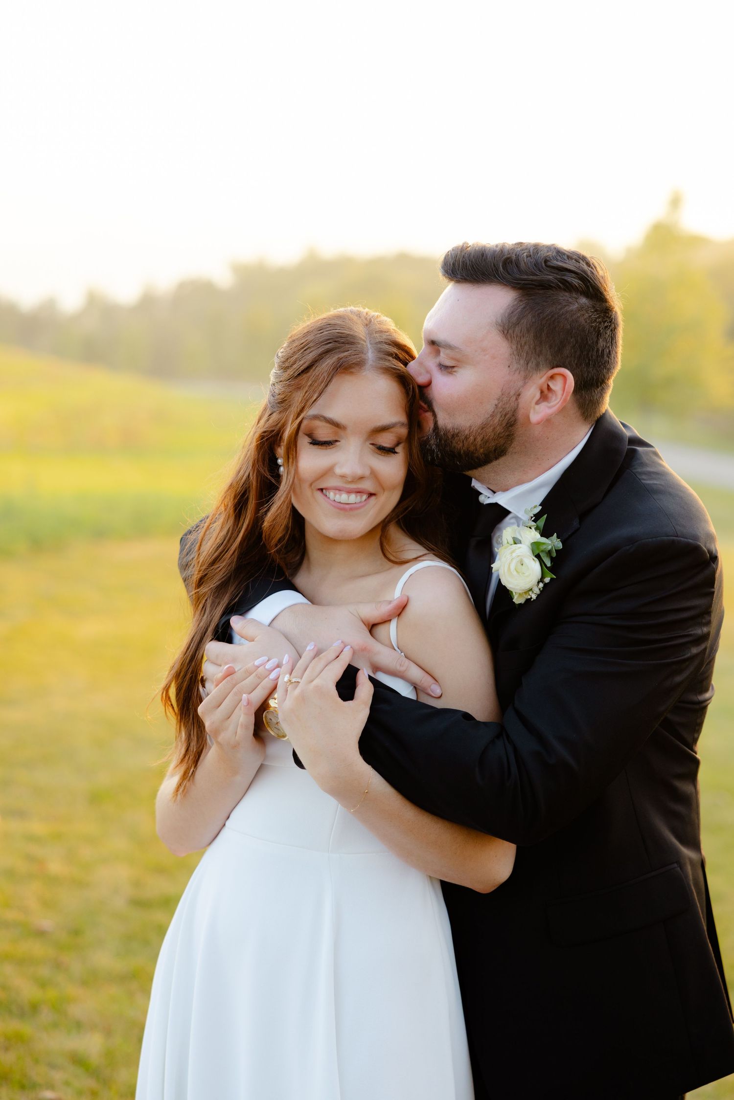 Intimate wedding portrait of couple embracing during golden hour with soft natural lighting.