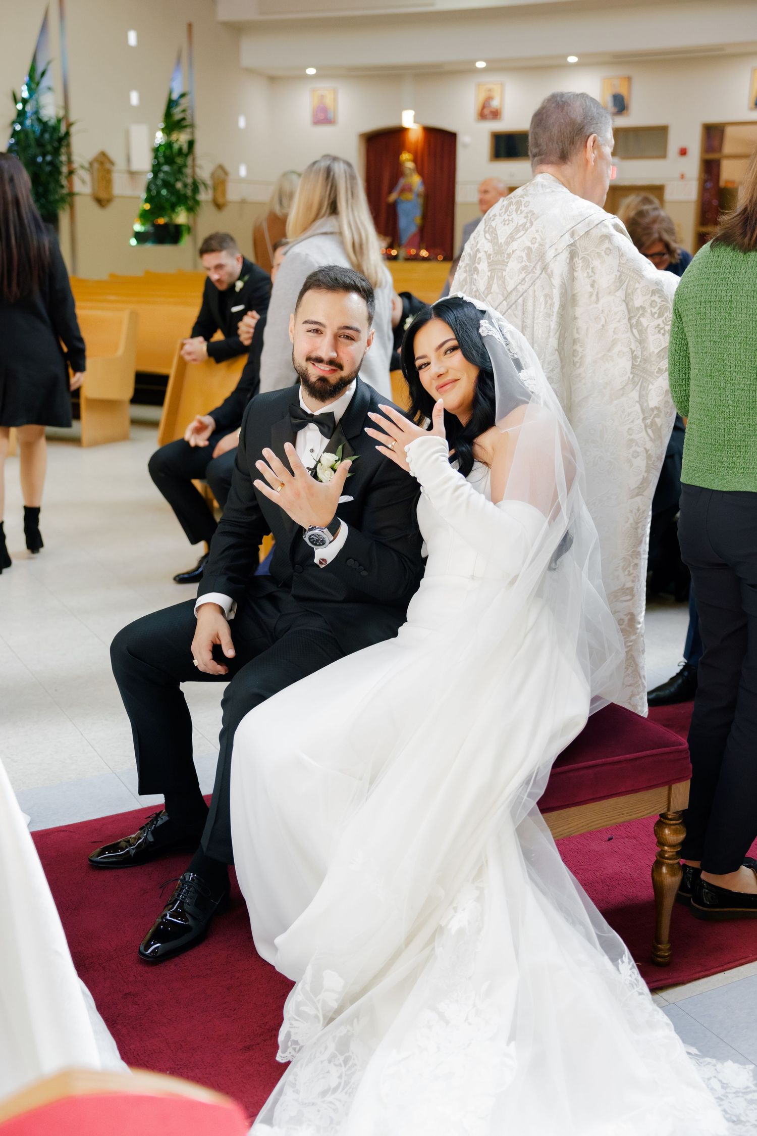 A newlywed couple sharing a joyful moment while seated in church pews.