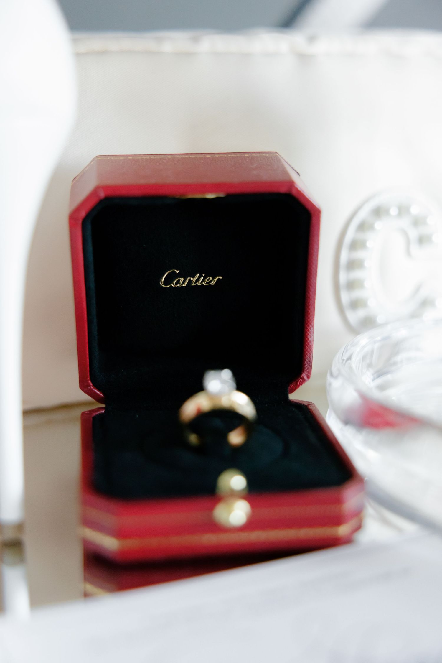 Elegant Cartier engagement ring displayed in signature red box on white surface.