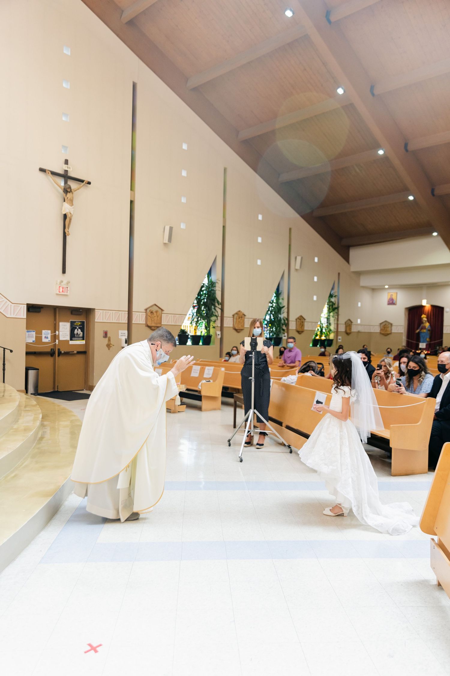 Religious ceremony taking place in modern church sanctuary with wooden beams and crucifix.