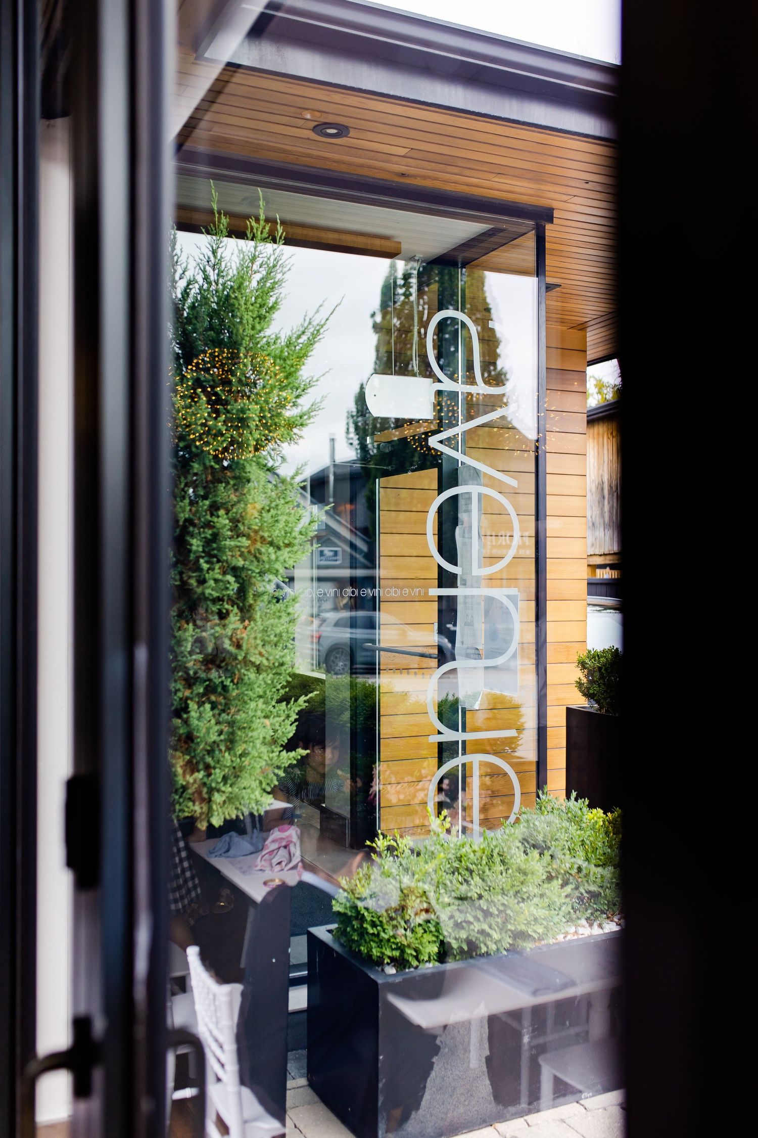 Modern restaurant exterior with glass doors and planters featuring the word 'evoke' on window.