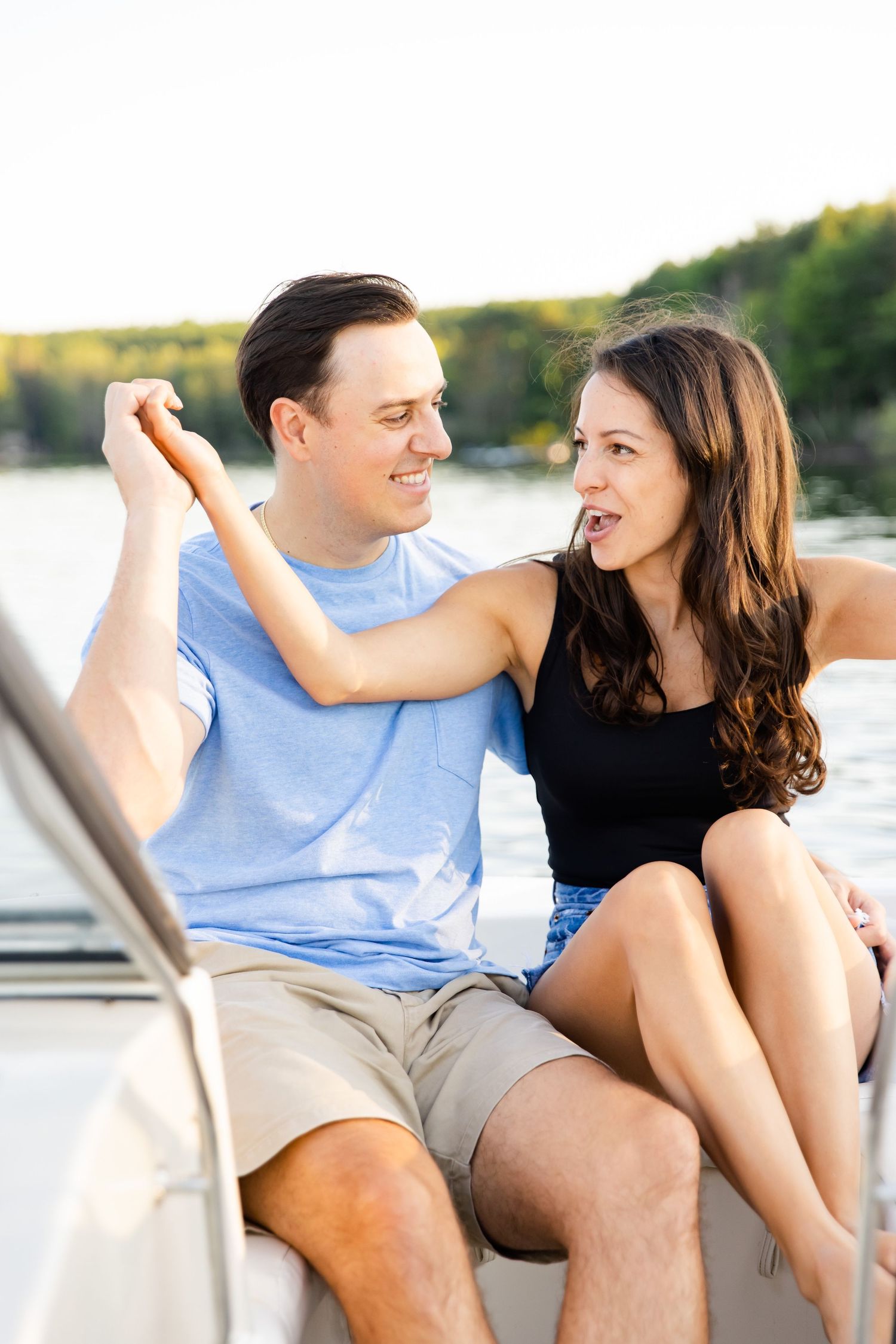 Playful moment between couple during boat photoshoot on sunny summer day.
